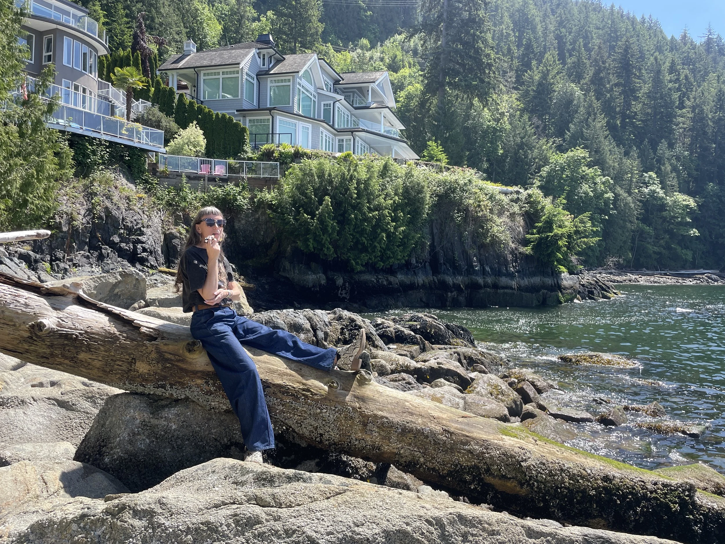 Rev cindy pincus clairvoyant counseling sitting on rocky shore with pine trees and ocean waves