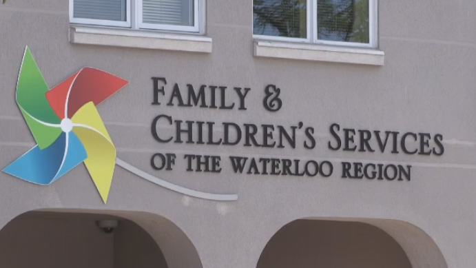 Sign for Family & Children's Services of the Waterloo Region on a building exterior, featuring a colorful pinwheel logo and windows above.