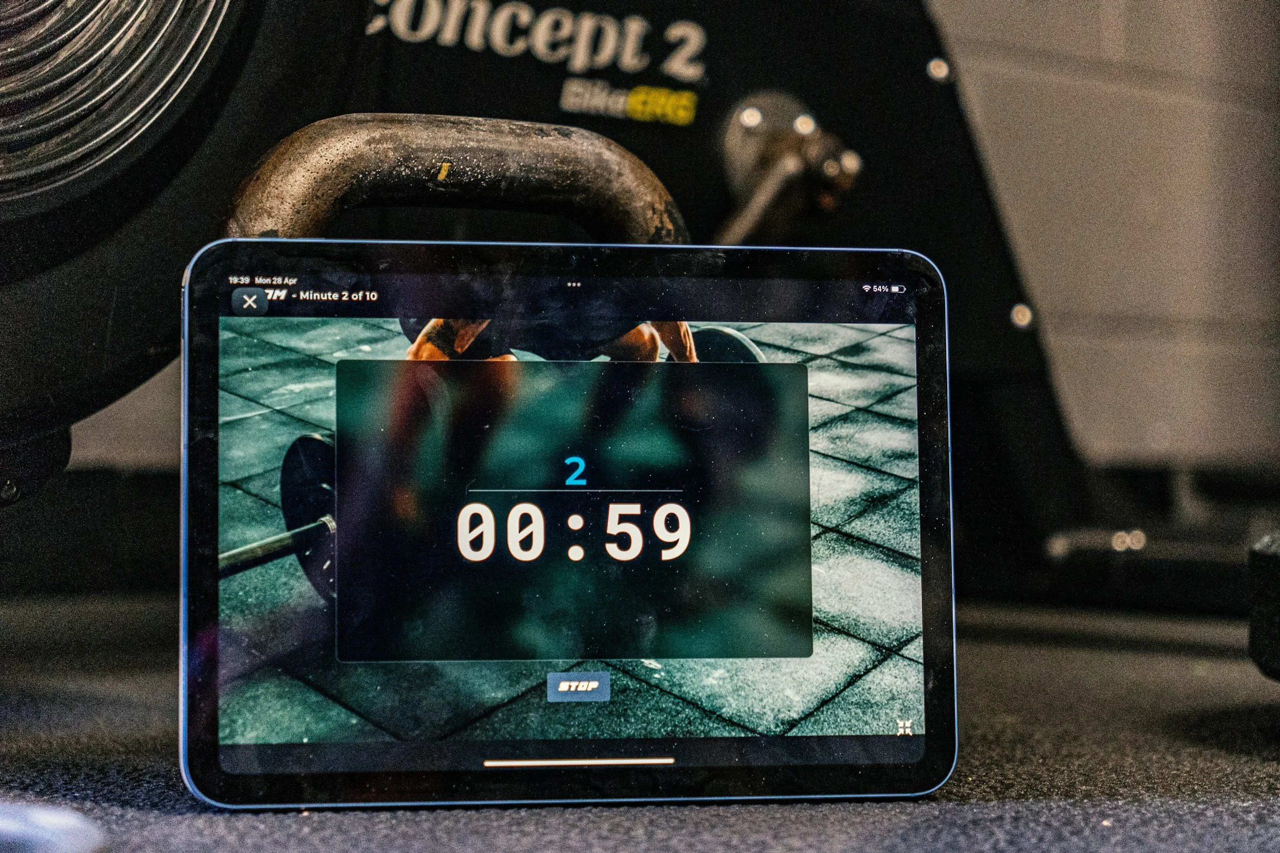 A smartphone displaying a digital timer set for 59 seconds, placed on the floor with a gym weight in the background.