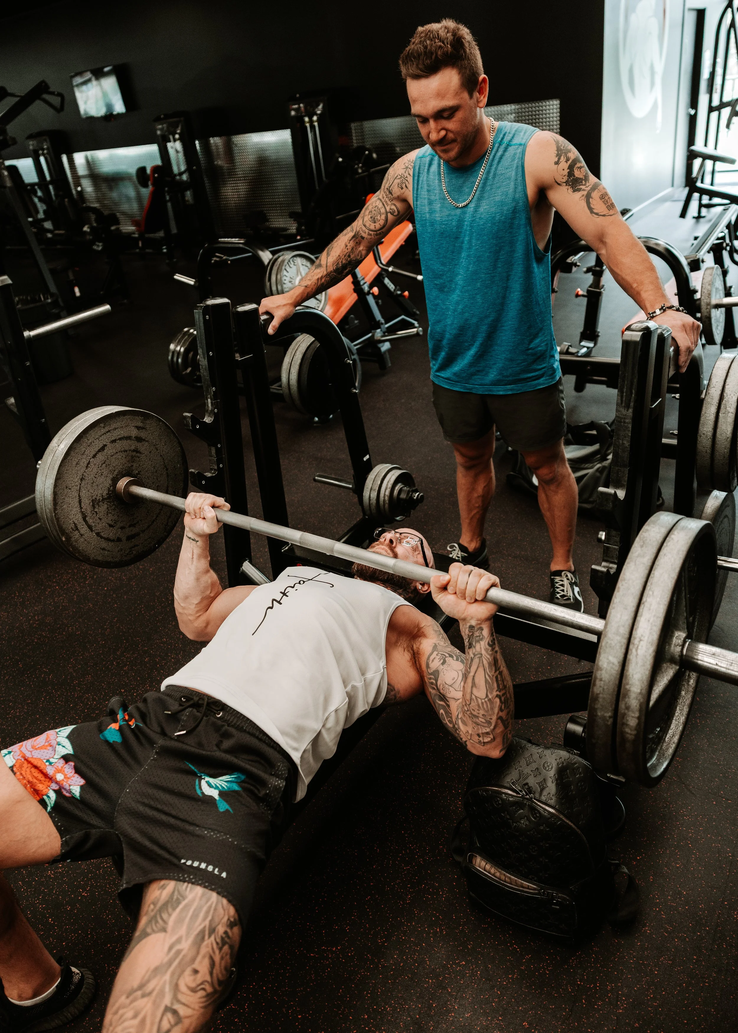 A person using a dumbbell for strength training in a gym. The person is wearing a watch and a striped shirt, with their arm muscles engaged.