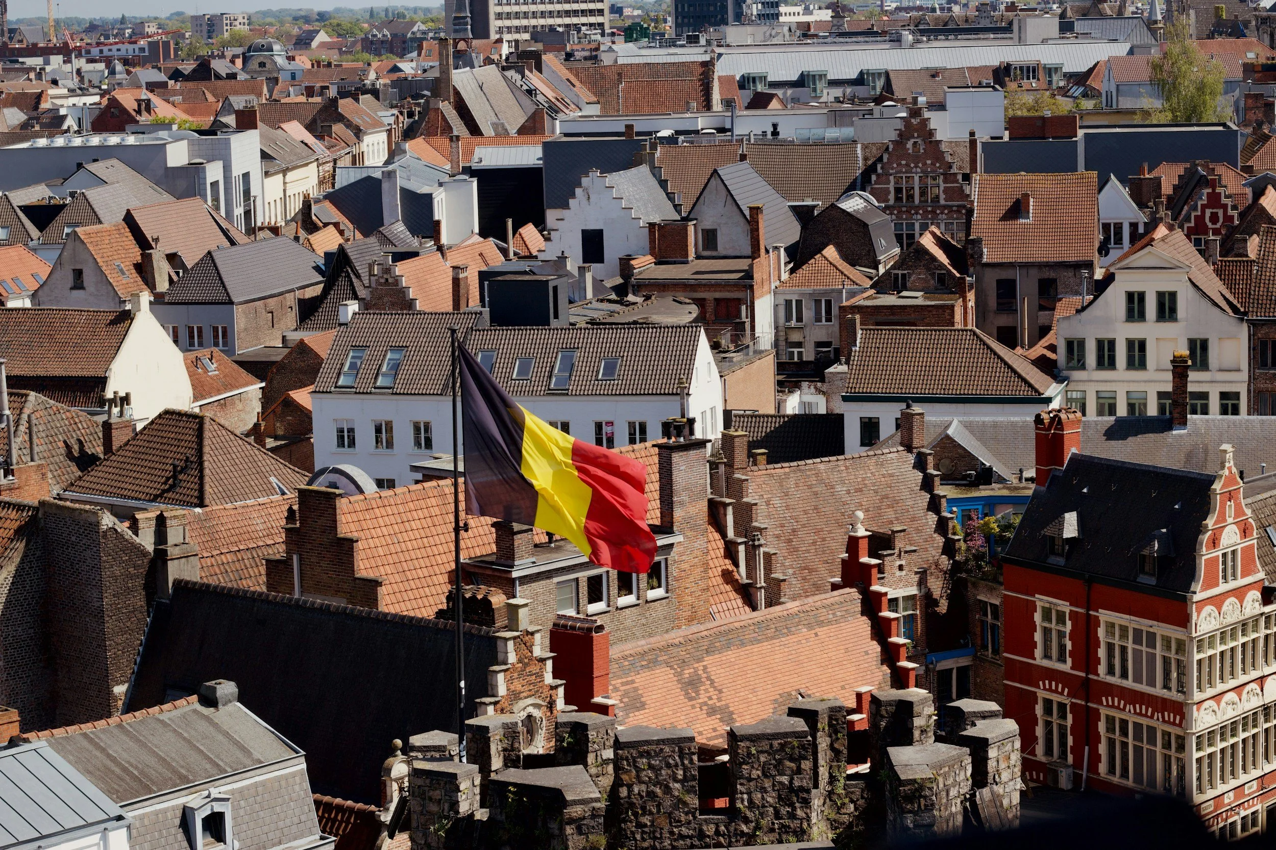 Belgian flag waving on top of buildings representing Belgian citizenship and nationality applications