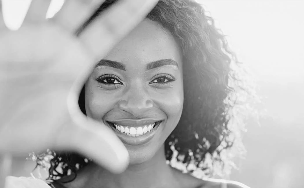 Smiling woman framing her face with hands, representing confidence after revision rhinoplasty surgery in the UK