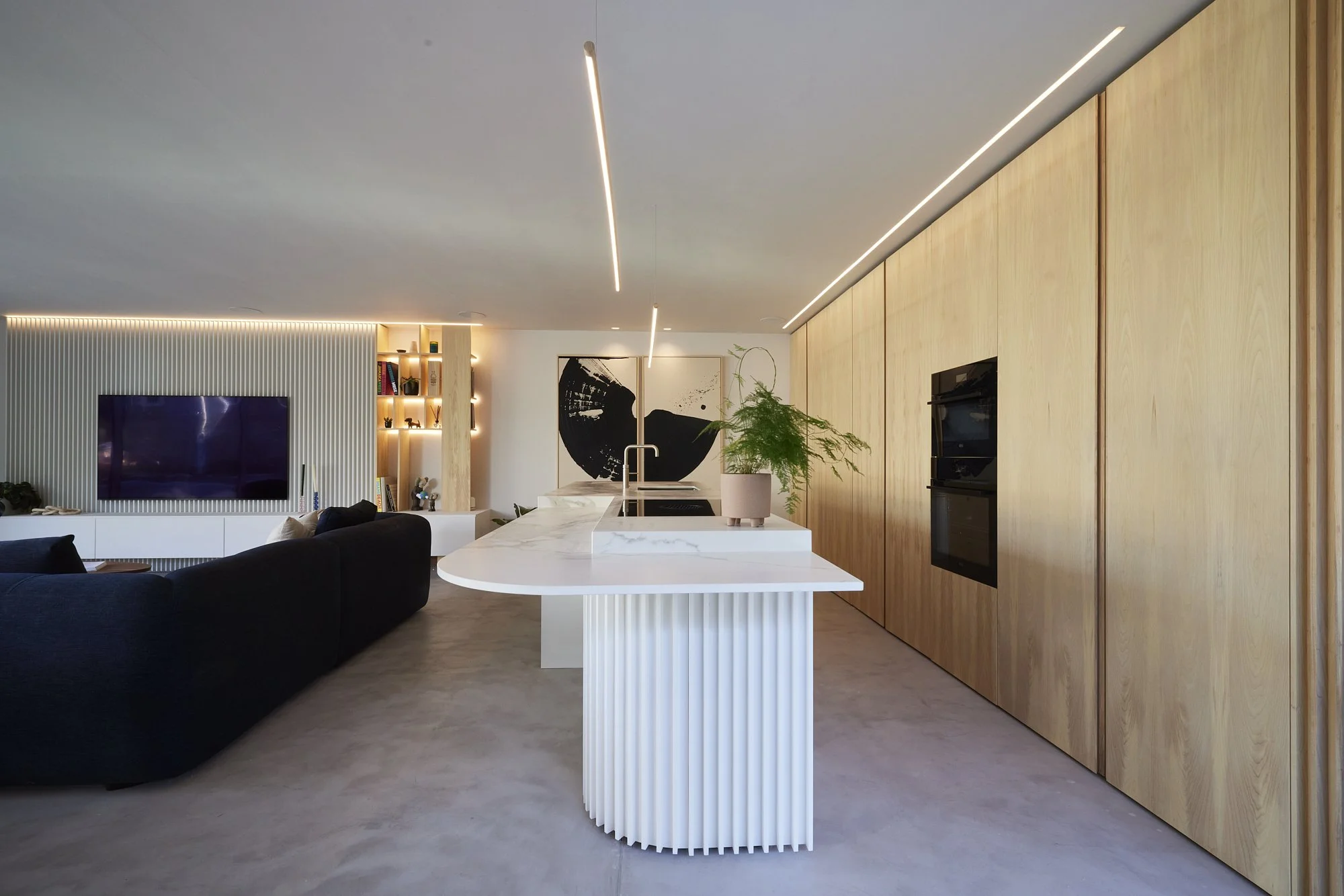 Bespoke kitchen with fluted island, oak cabinetry and integrated lighting within open-plan living space at Pavillon by Boyes Design