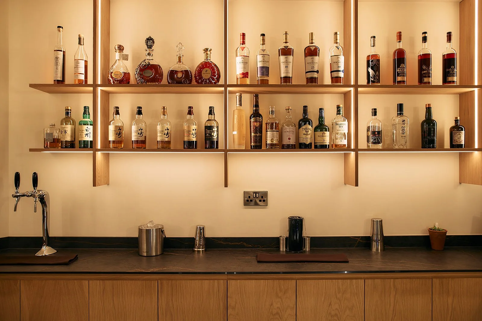 Detail of bespoke bar joinery with bottle display and lighting at Restaurant Sat Bains Nottingham