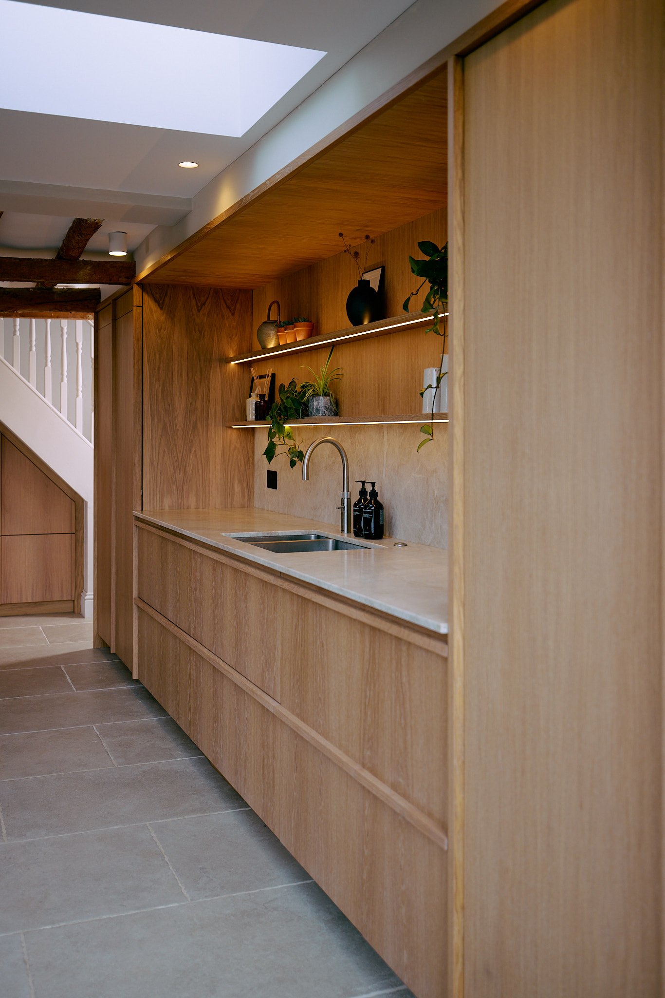 Oak kitchen cabinetry with open shelving and stone worktops