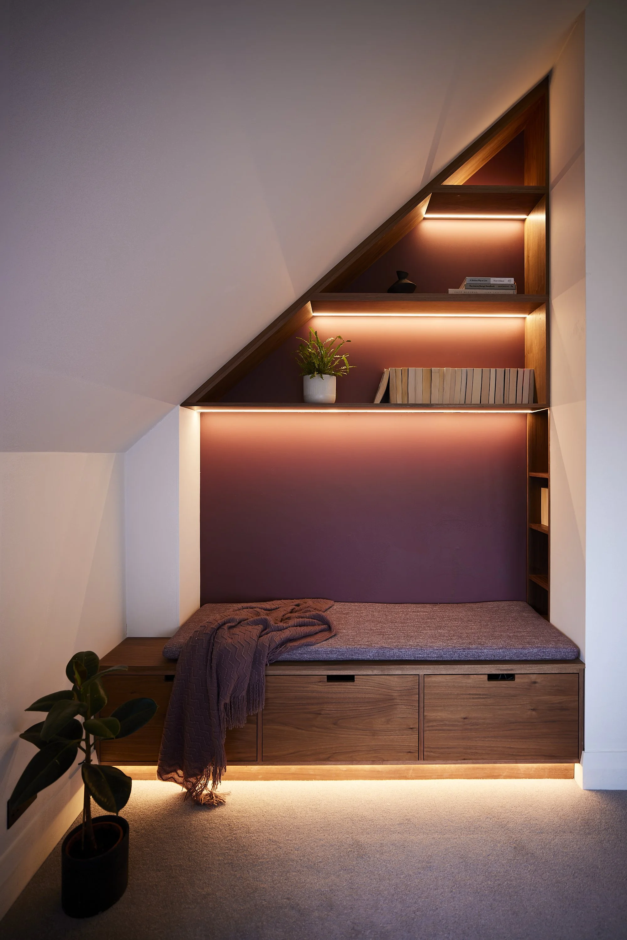 Custom shelving designed to follow a sloped bedroom ceiling with integrated lighting