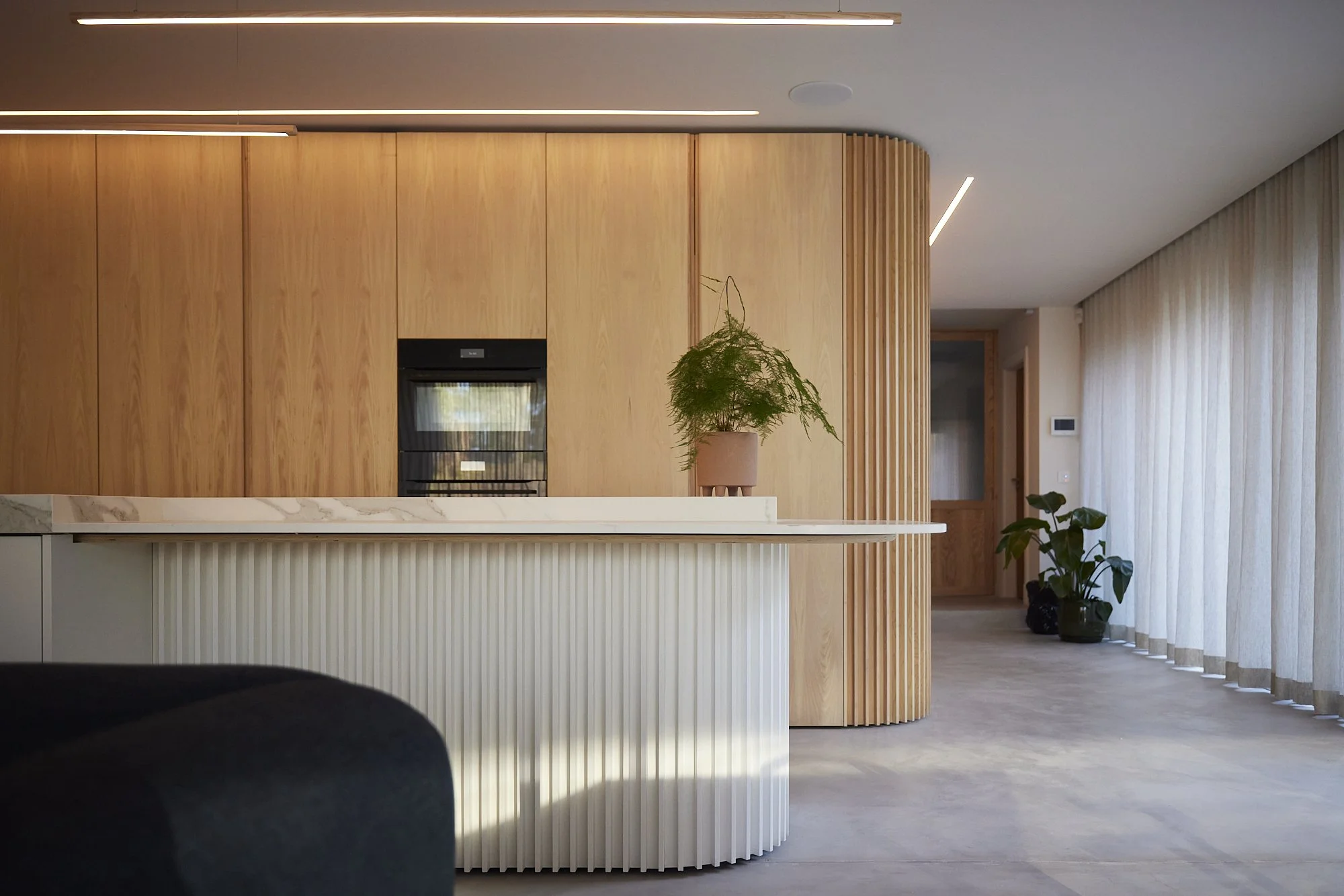 Bespoke oak kitchen with curved joinery wall and integrated storage at Pavillon by Boyes Design