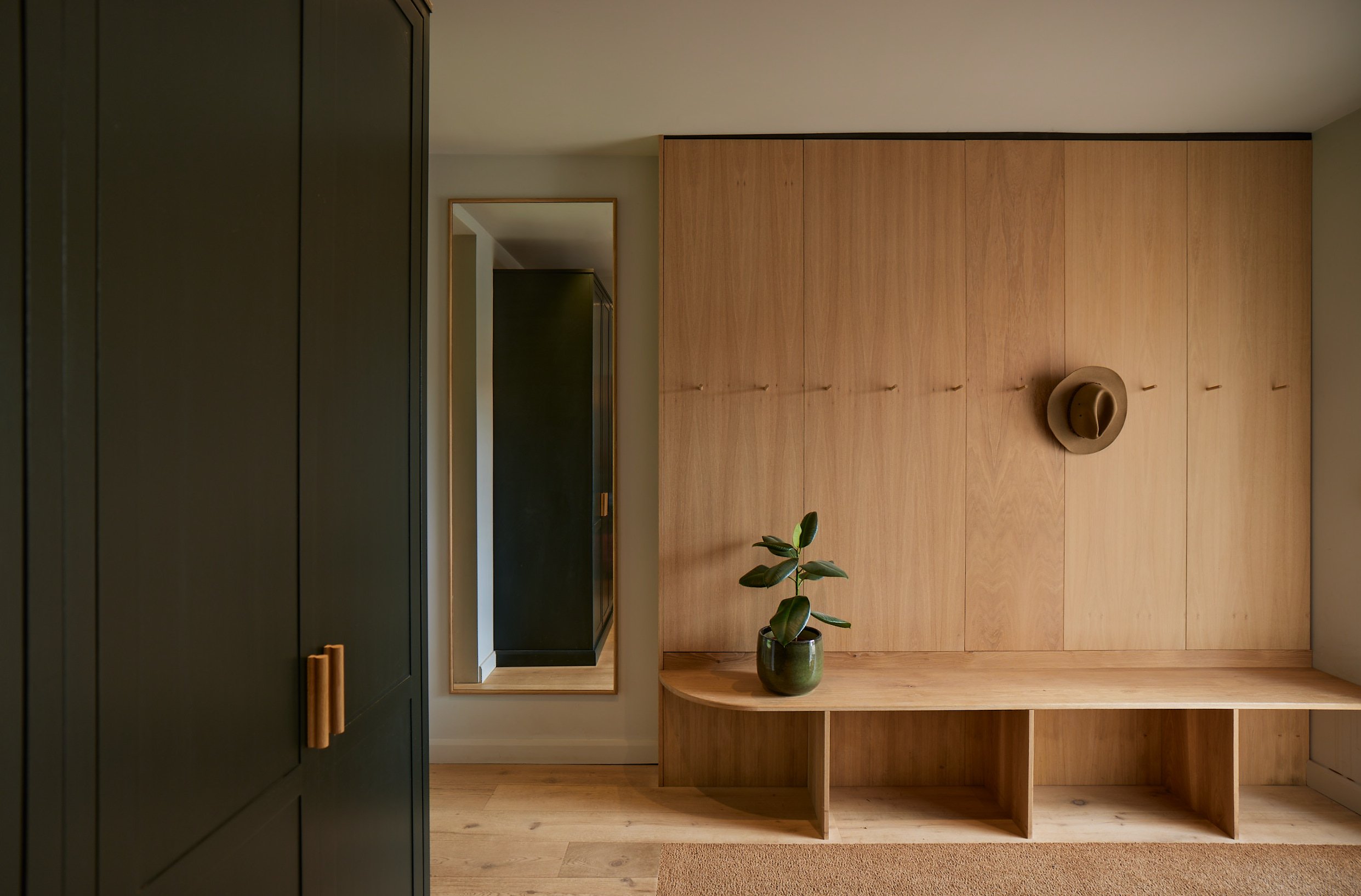 Bespoke oak bootroom with integrated bench seating and concealed storage at Wynstay House in Nottinghamshire by Boyes Design