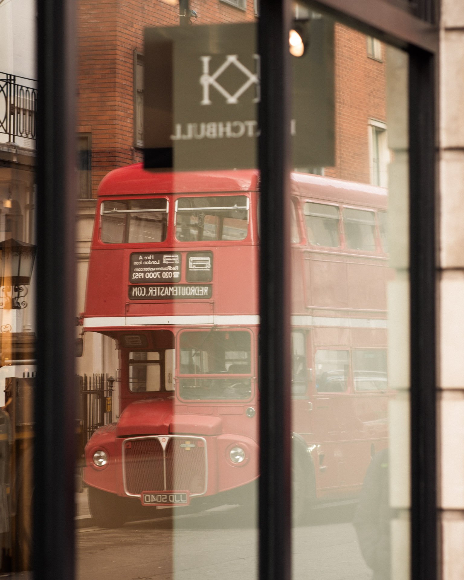 A vintage double decker bus reflected in a shop window on Savile Row, London.