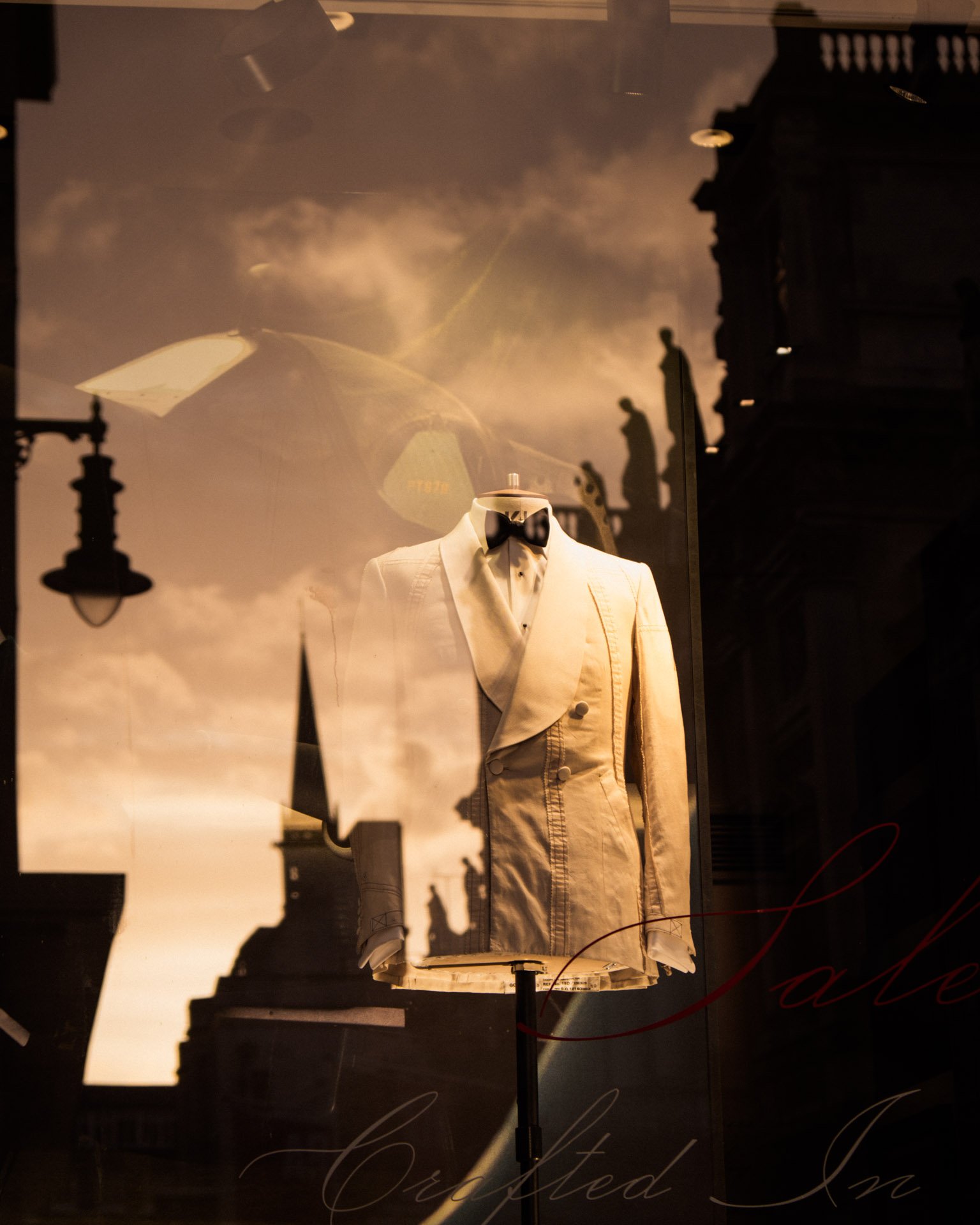 A suit reflected in a shop window at sunset on Savile Row, London