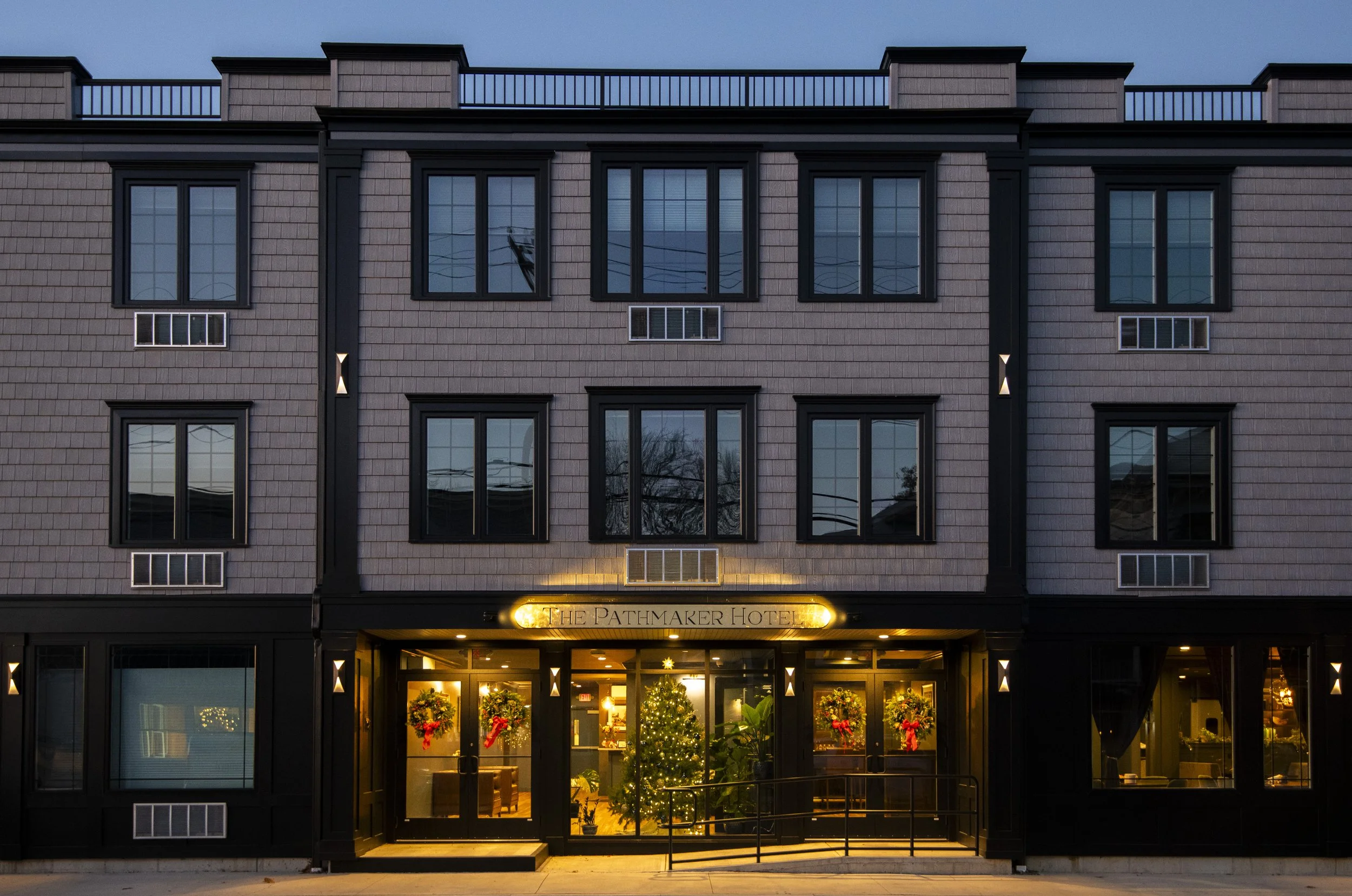 Front exterior of The Pathmaker Hotel at dusk, showing the entrance decorated with Christmas wreaths and a Christmas tree inside