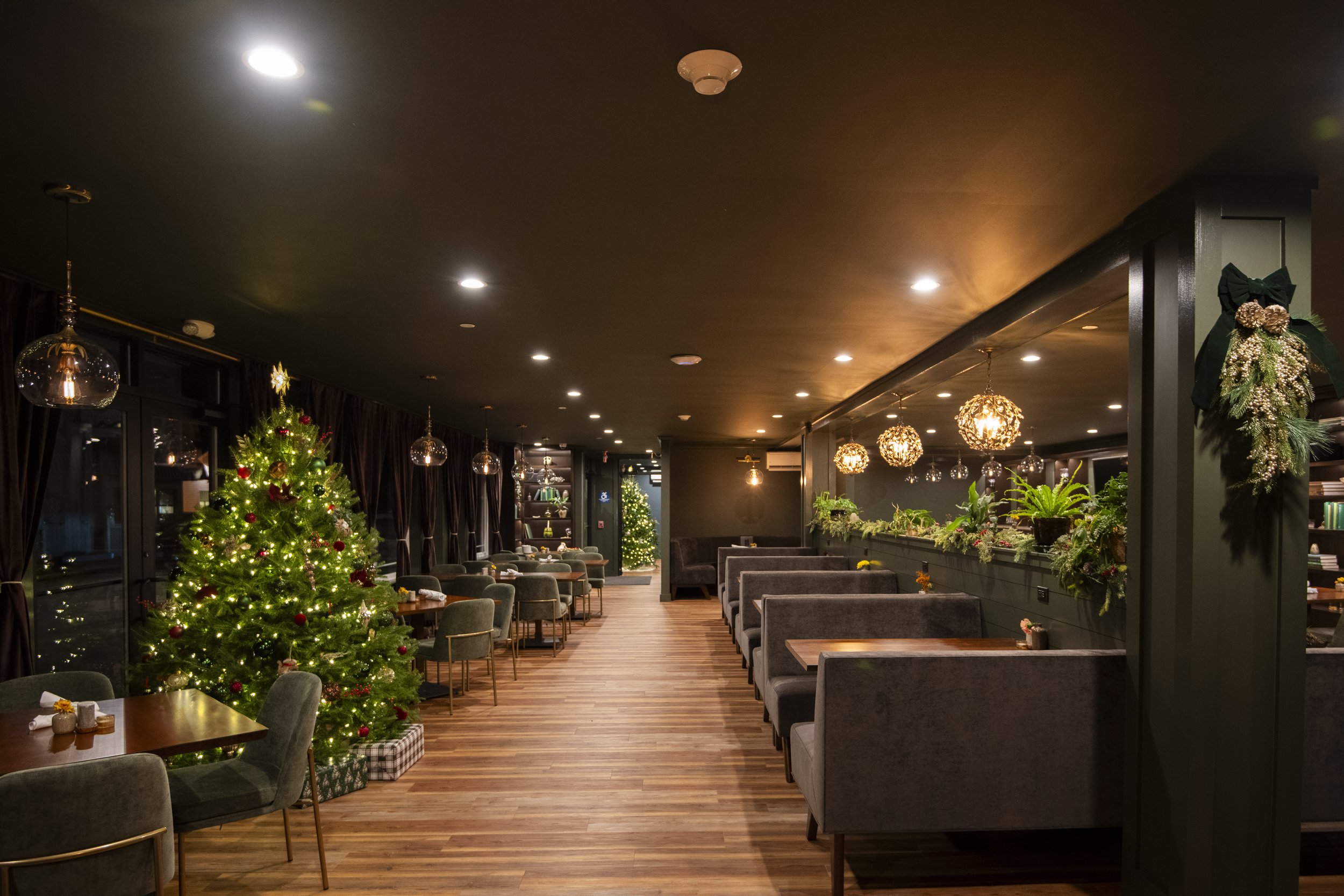 Interior of a restaurant decorated for Christmas with a Christmas tree, holiday ornaments, and festive lighting.