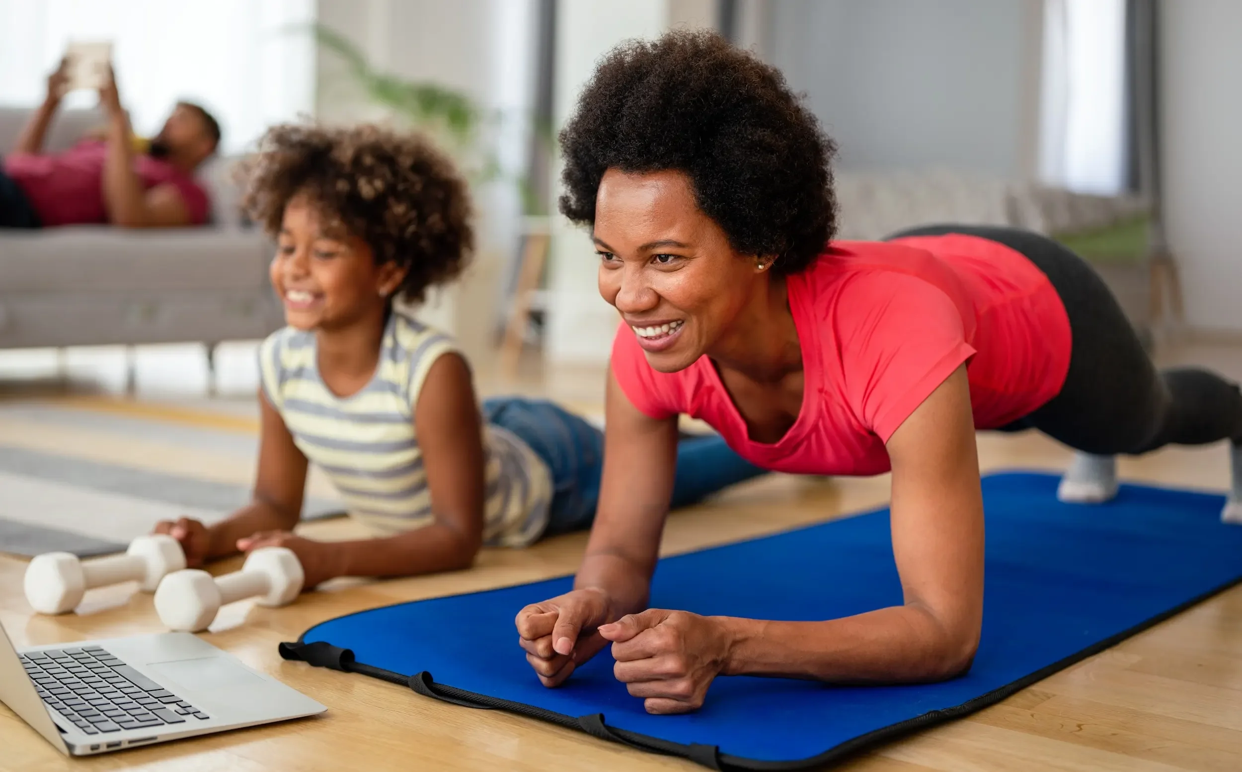 An African-American woman working out with her daughter.