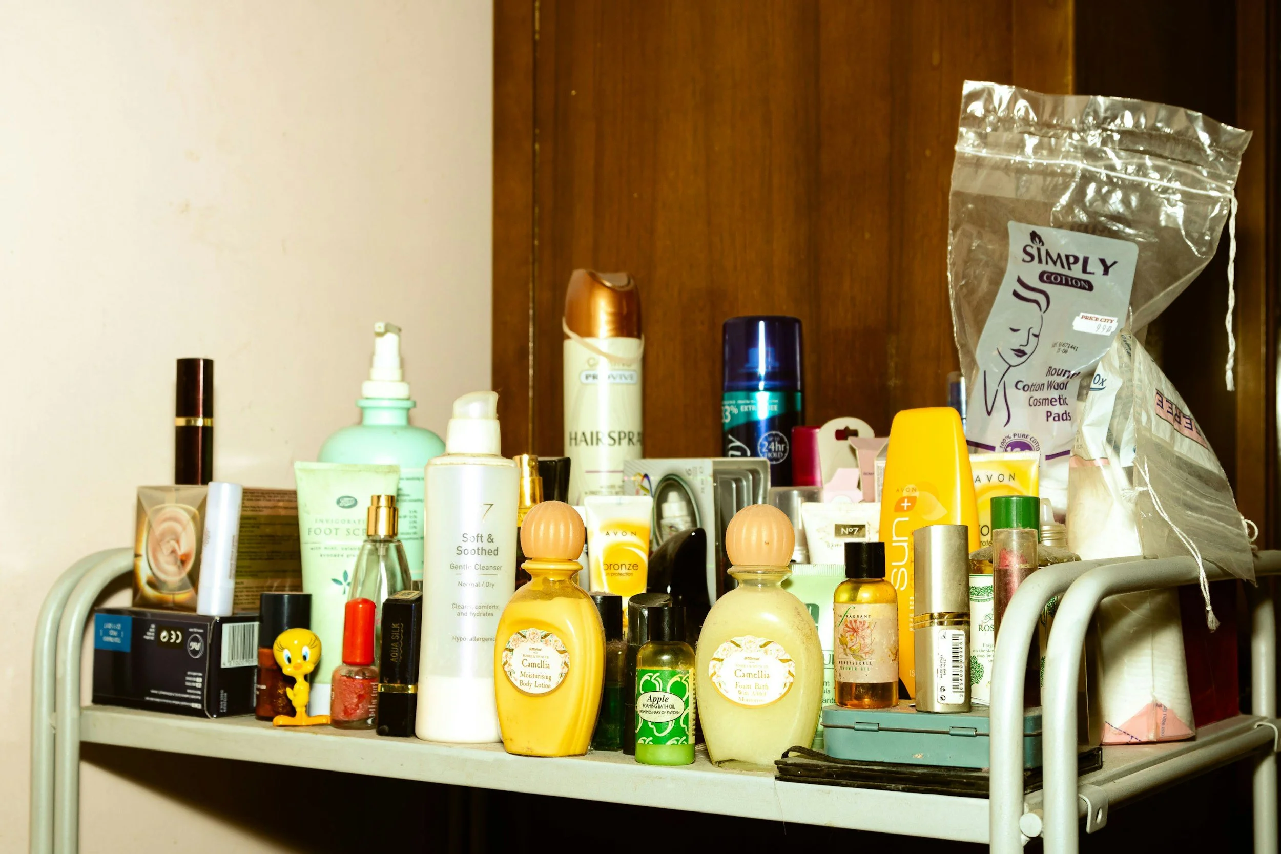 a metal shelf holding hair care products, makeup products, and other beauty products.