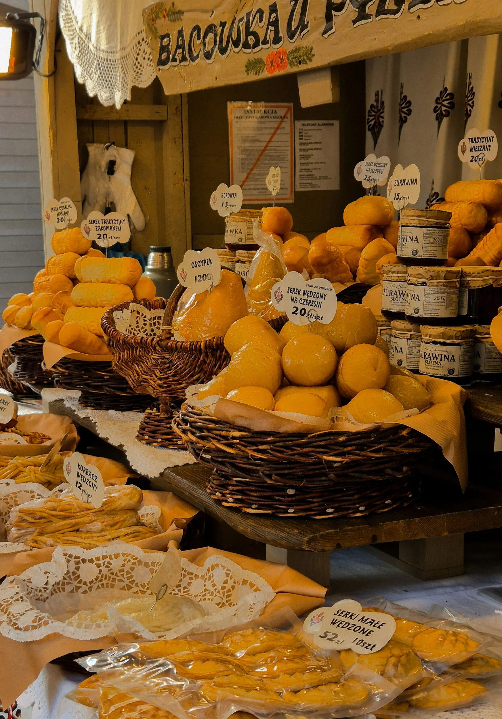 Oscypek sold in a store with other cheeses stacked on a table.