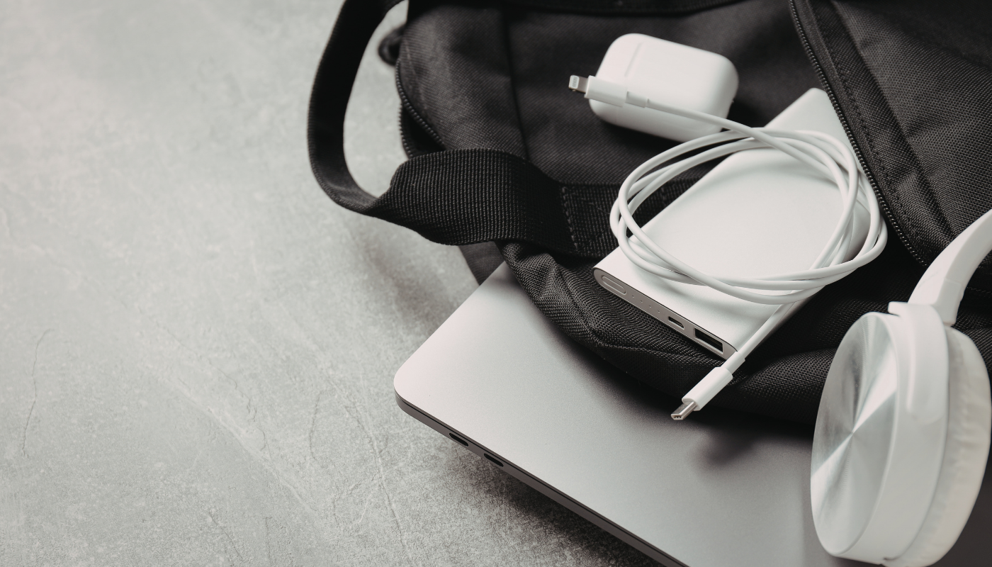 a black backpack with headphones, battery pack, laptop, and phone charger.