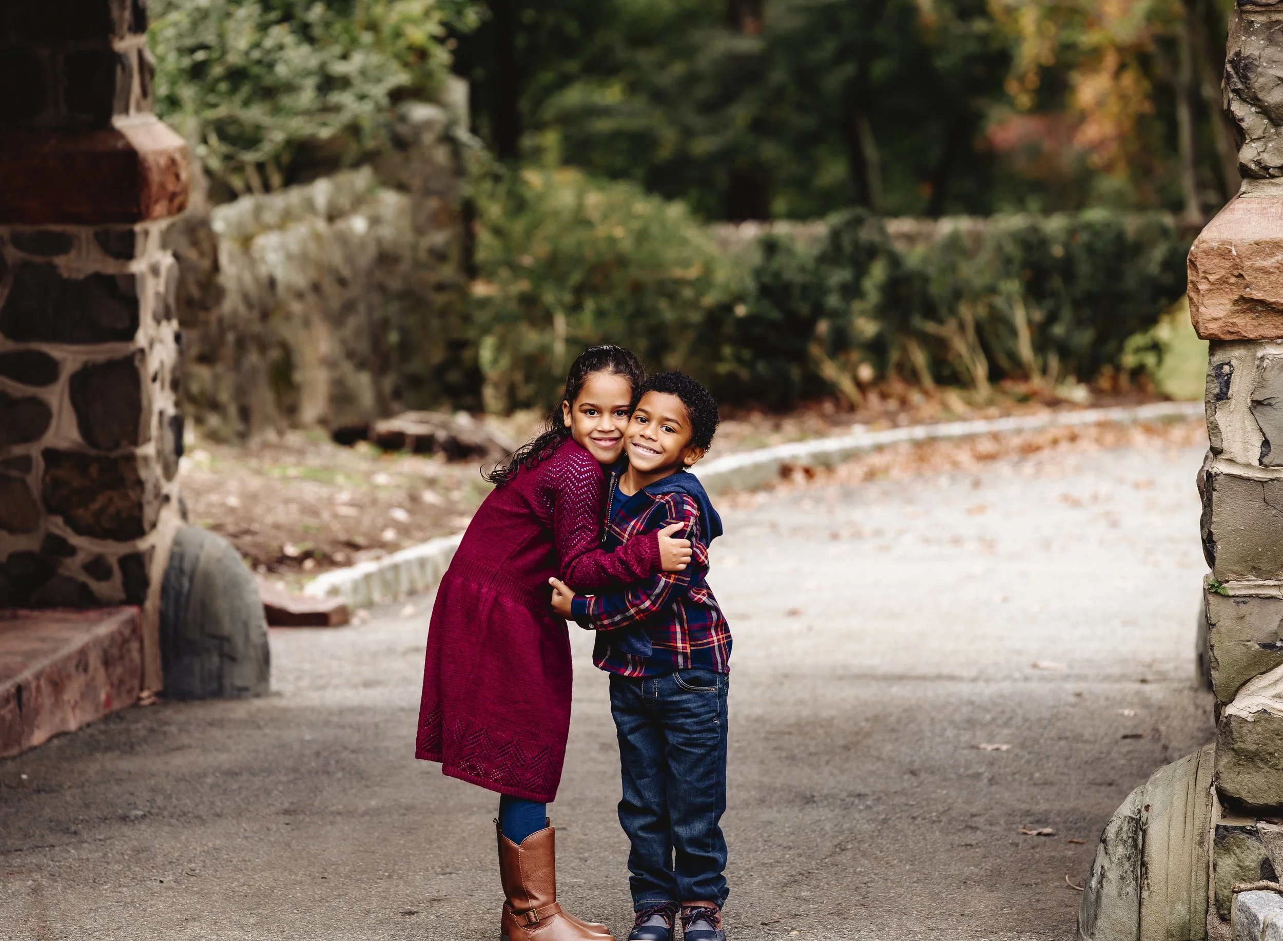 Two children, a girl and a boy, hugging and smiling outdoors.