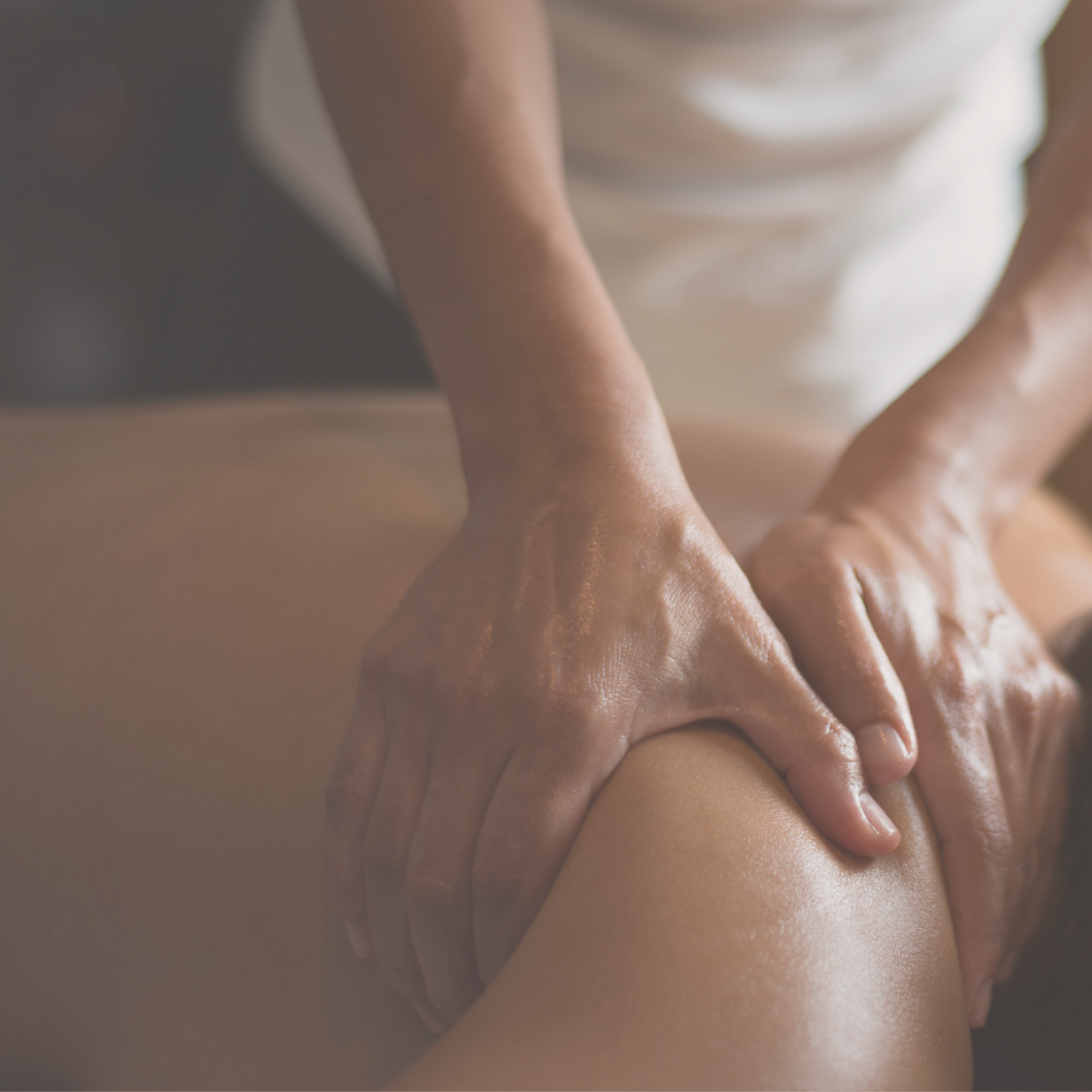 Close-up of a massage therapist's hands giving a massage to a person's thigh.
