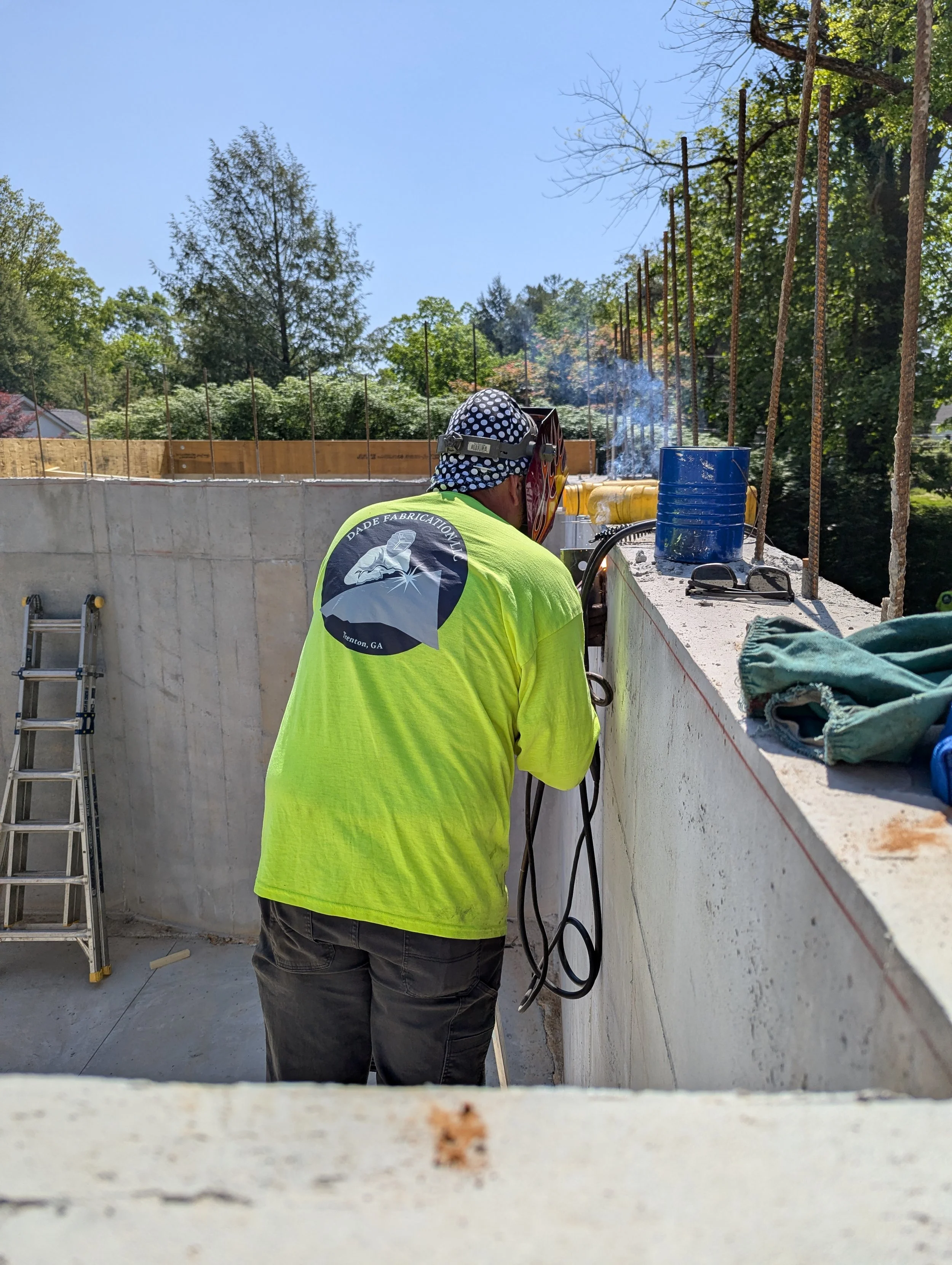 Dade Fabrication field welder working on site from the top of a concrete wall