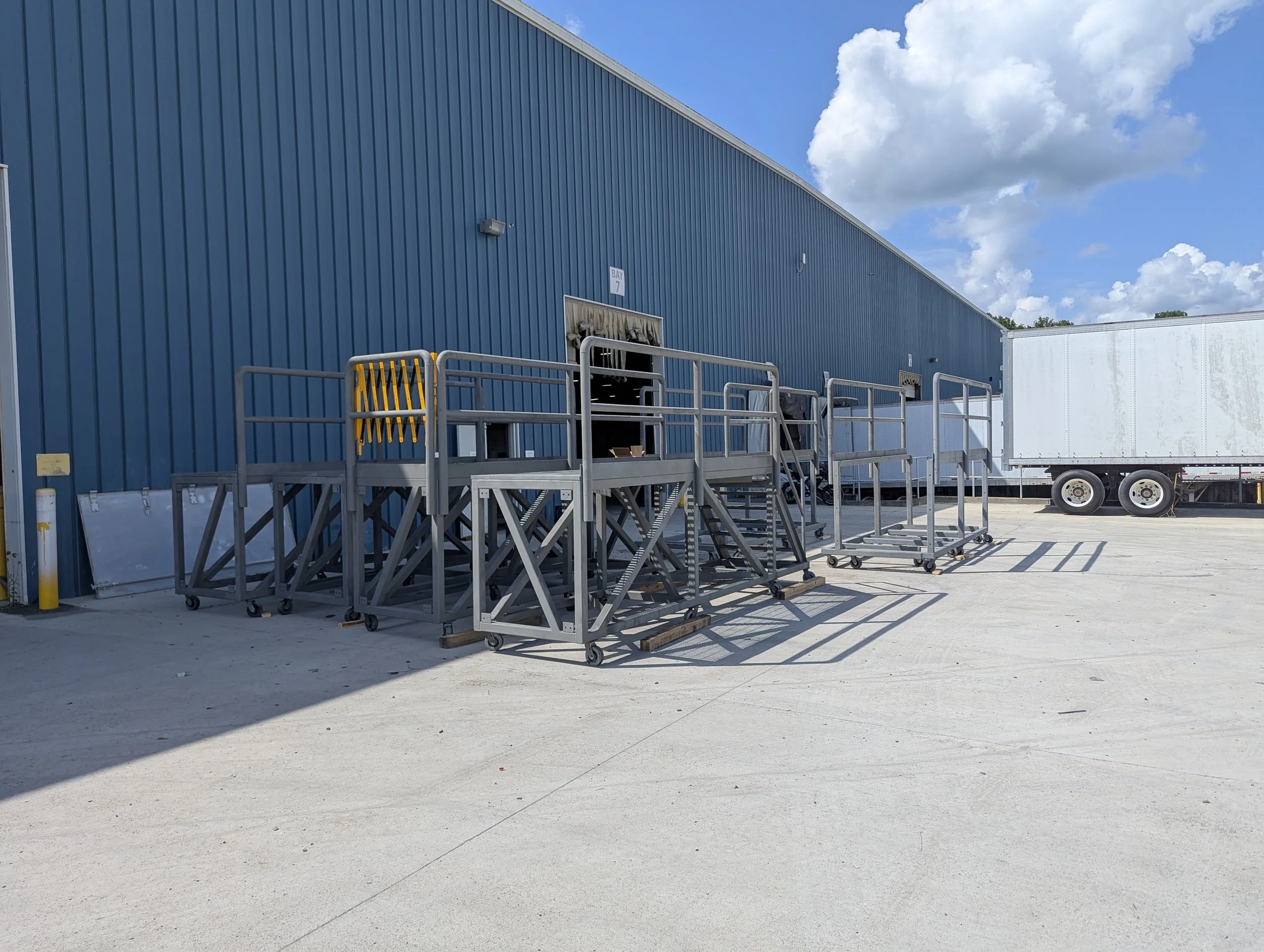 Welded steel trailer access platforms with stairs and guardrails, delivered by Dade Fabrication