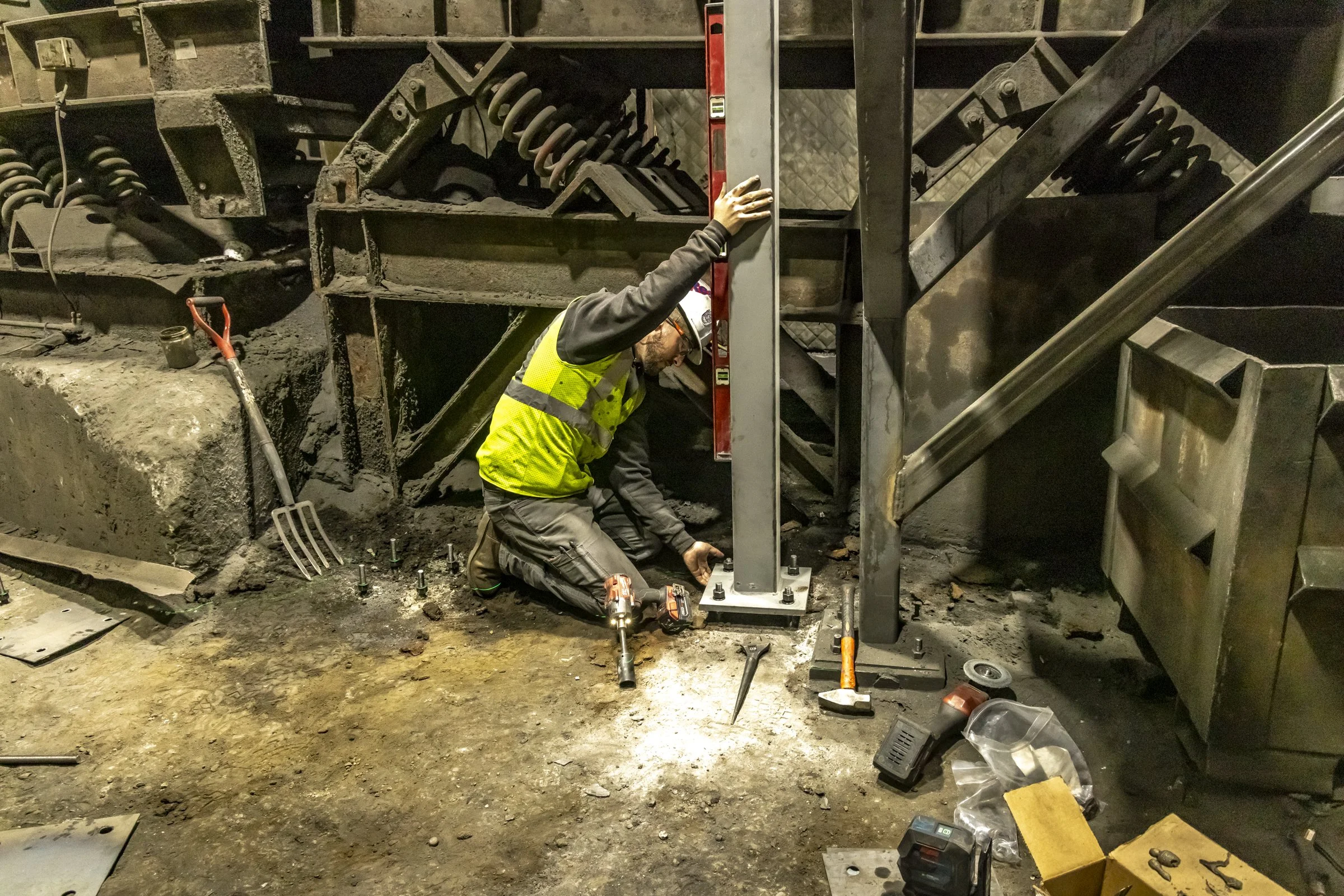 Dade Fabrication crew member plumbing a steel column and setting base plates on site