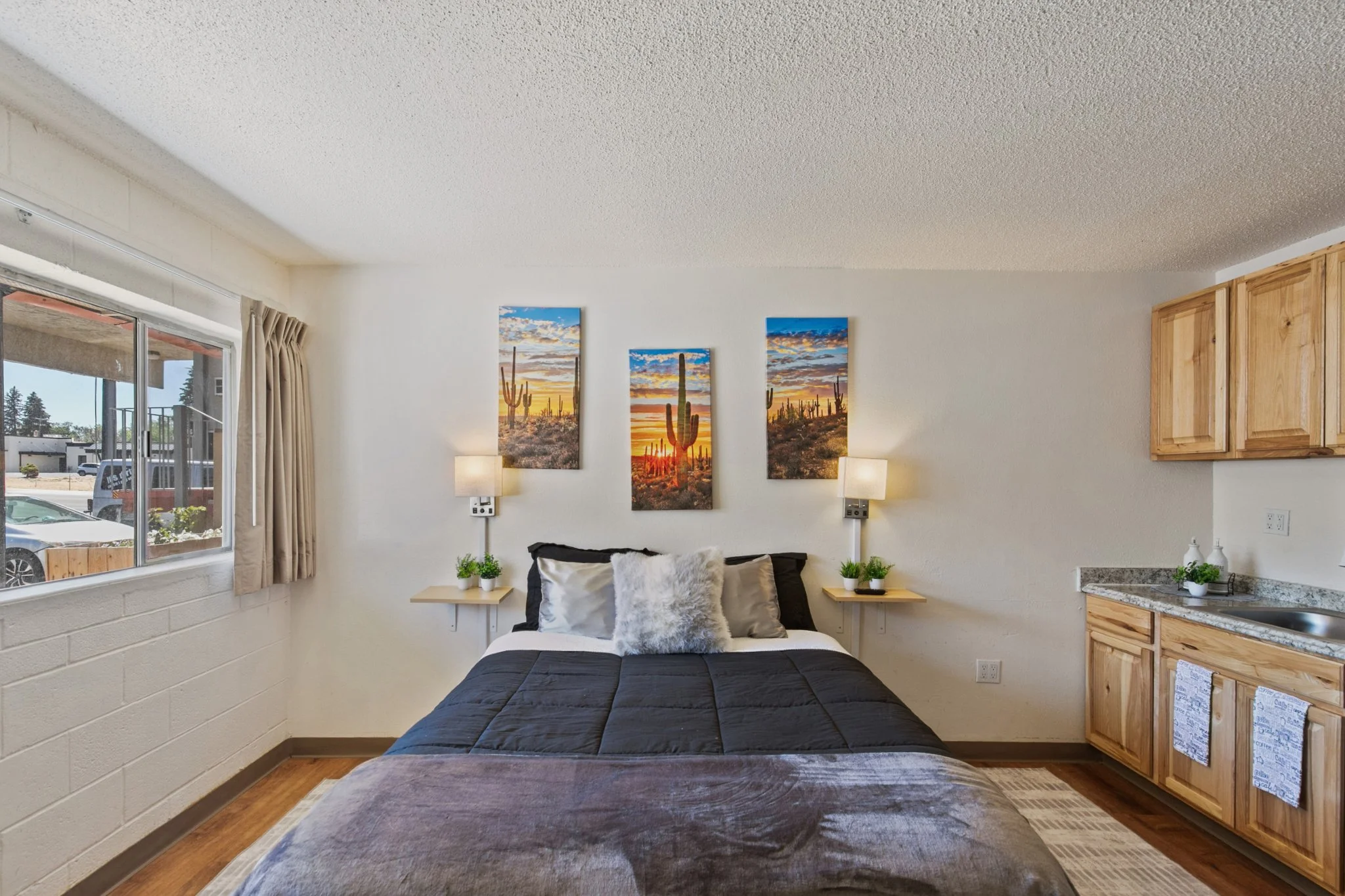 A bedroom with a bed, wall decorations, and a window with beige curtains.