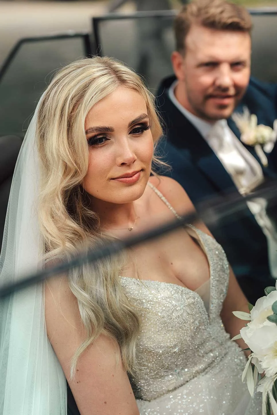 A luminous bride, radiating elegance, seen through the window of a classic vehicle on her wedding day in Brabant, captured with artistry.