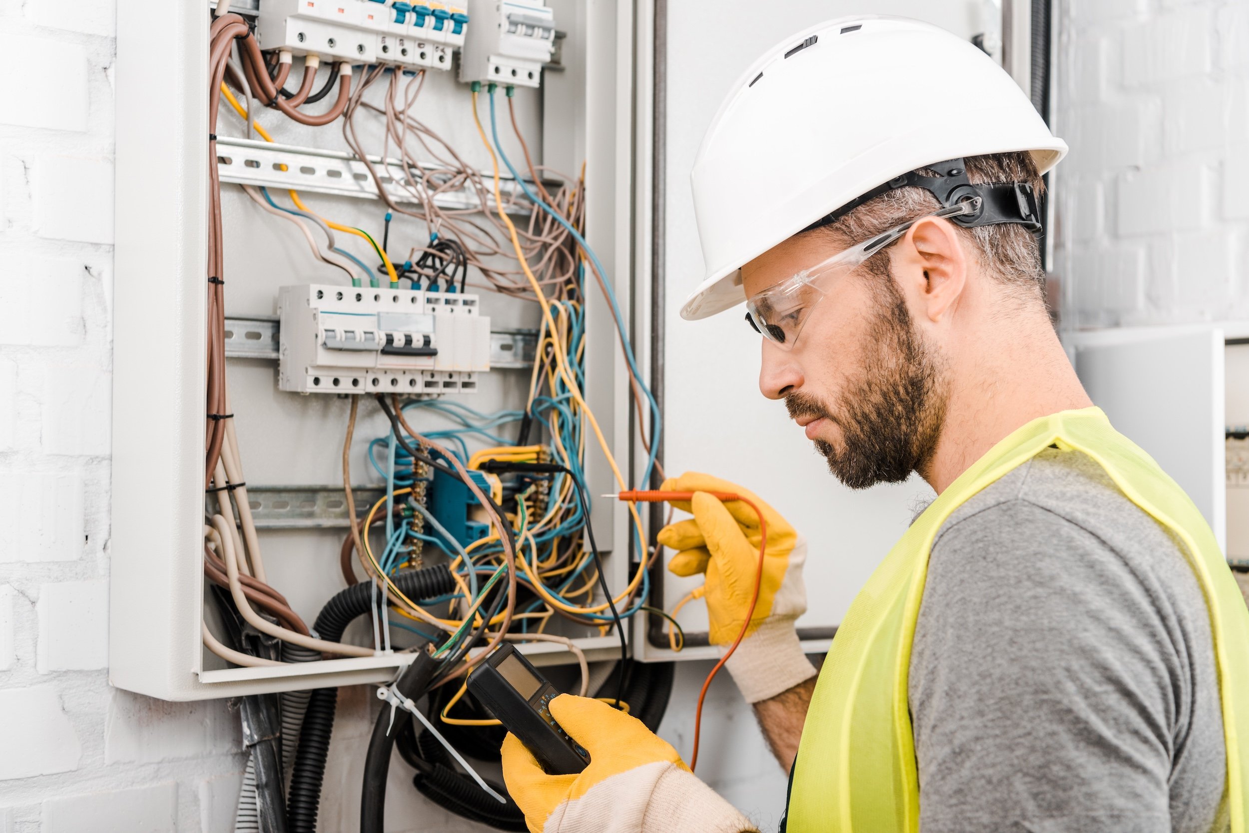 electrician checking electrical box with multimetr in corridor (Copy) (Copy)
