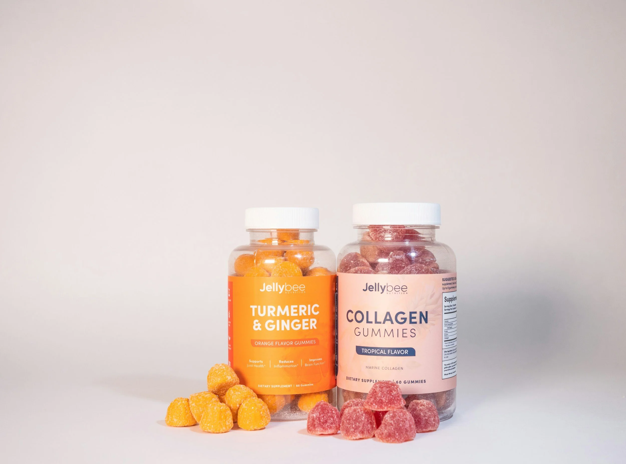 Two bottles of Jellybee gummies, one labeled turmeric and ginger behind the other labeled collagen with pink gummies in front of each bottle.