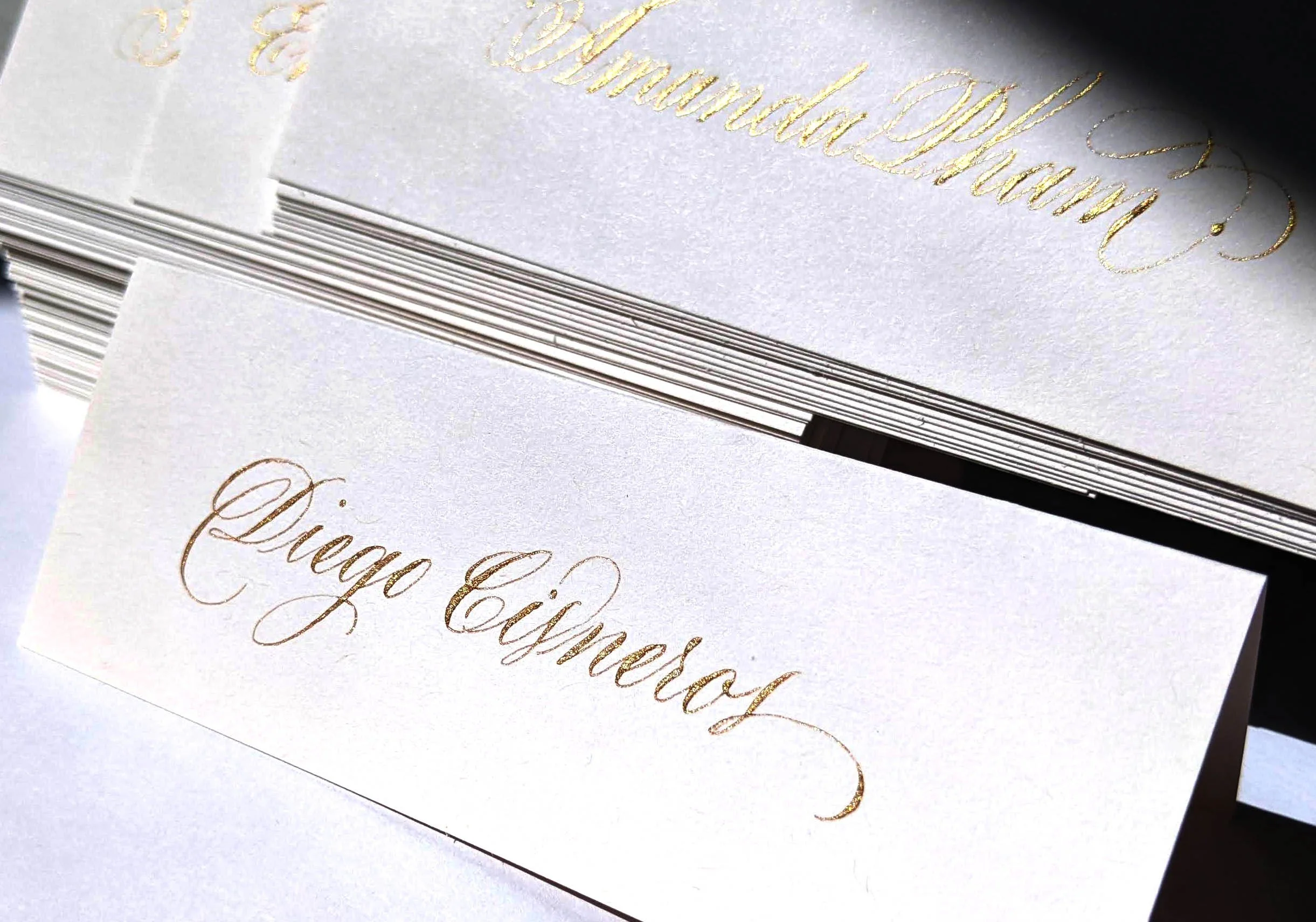 White tent place cards in gold ink hand lettering of first and last names.