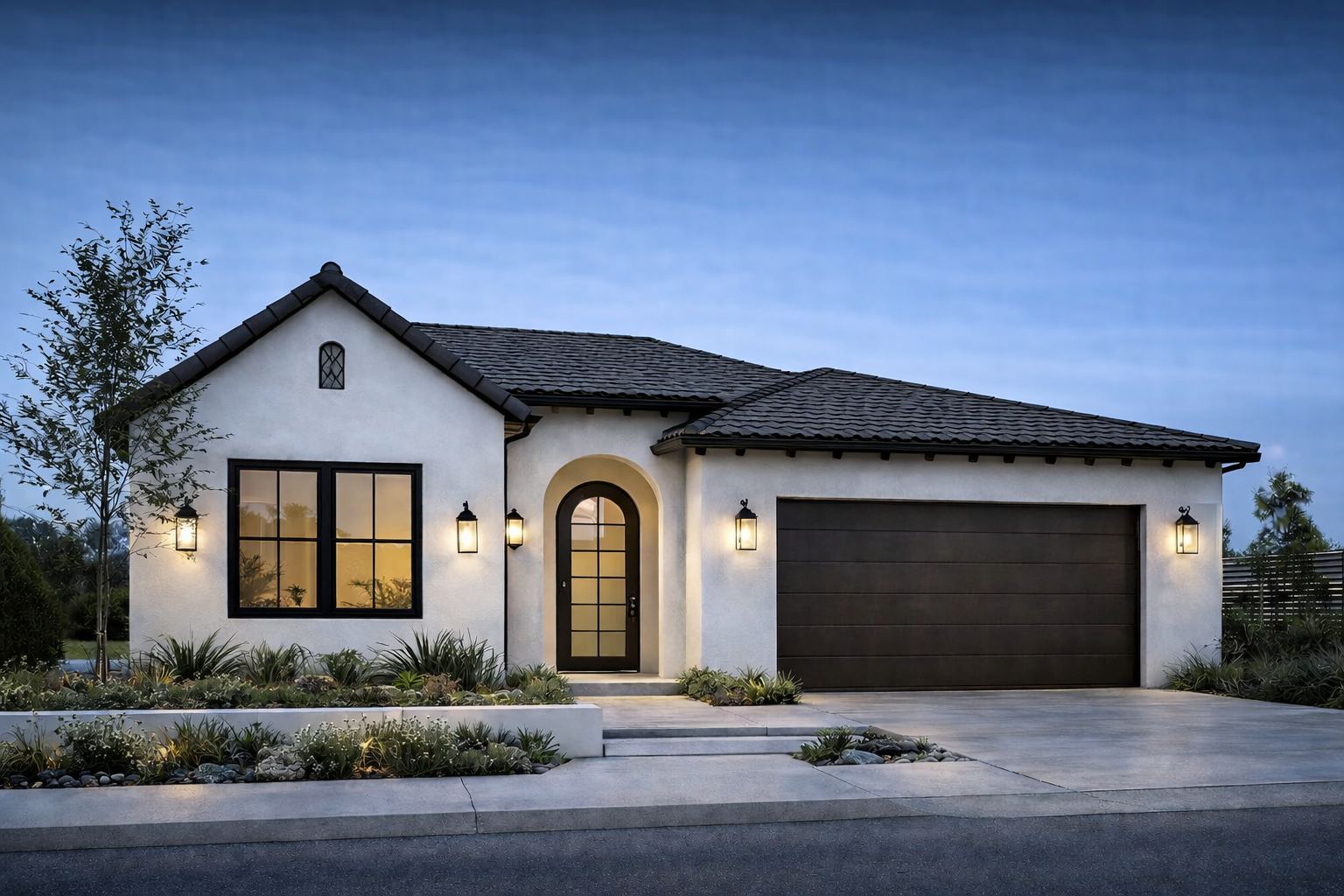Modern single-story house with white exterior, black window frames, and a black garage door, illuminated by exterior lights, with a landscaped front yard and a clear blue sky at dusk.