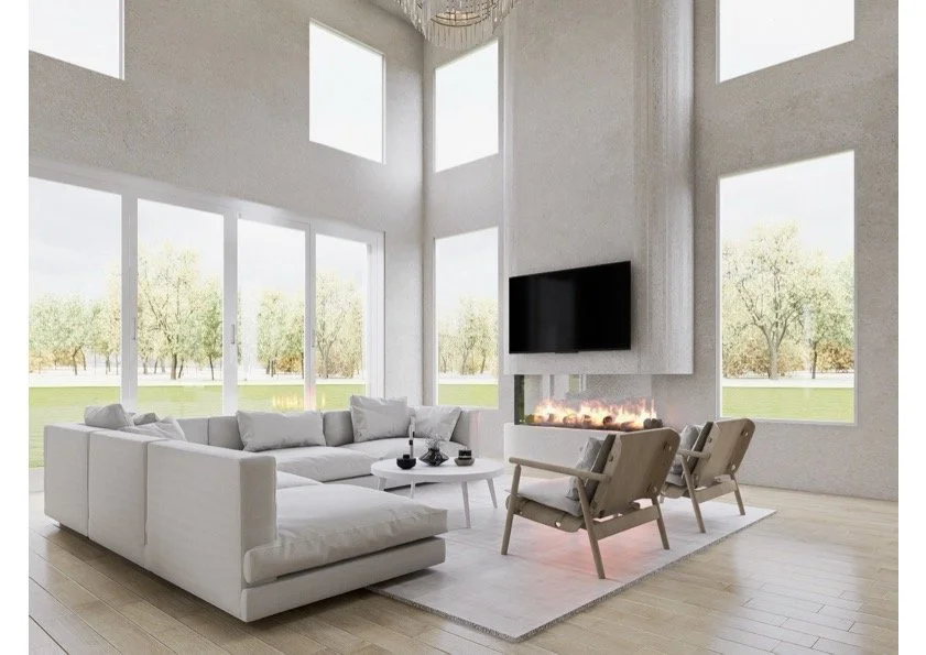 Modern living room with large windows, white sectional sofa, two beige armchairs, a wall-mounted flat-screen TV, and a fireplace, with a view of trees outside.