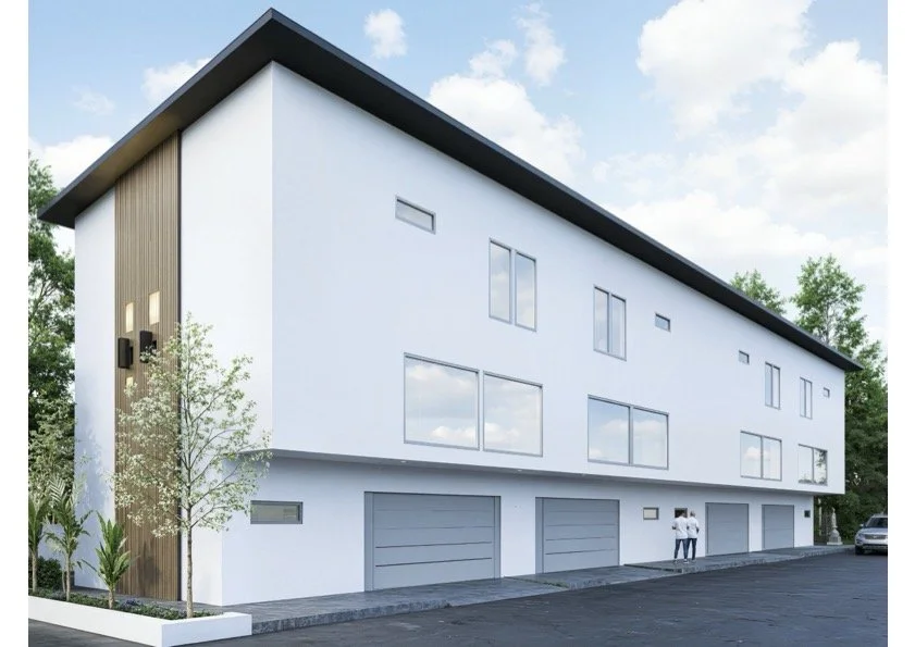 Modern multi-story building with white exterior, large windows, and garage doors, surrounded by trees and parking area.