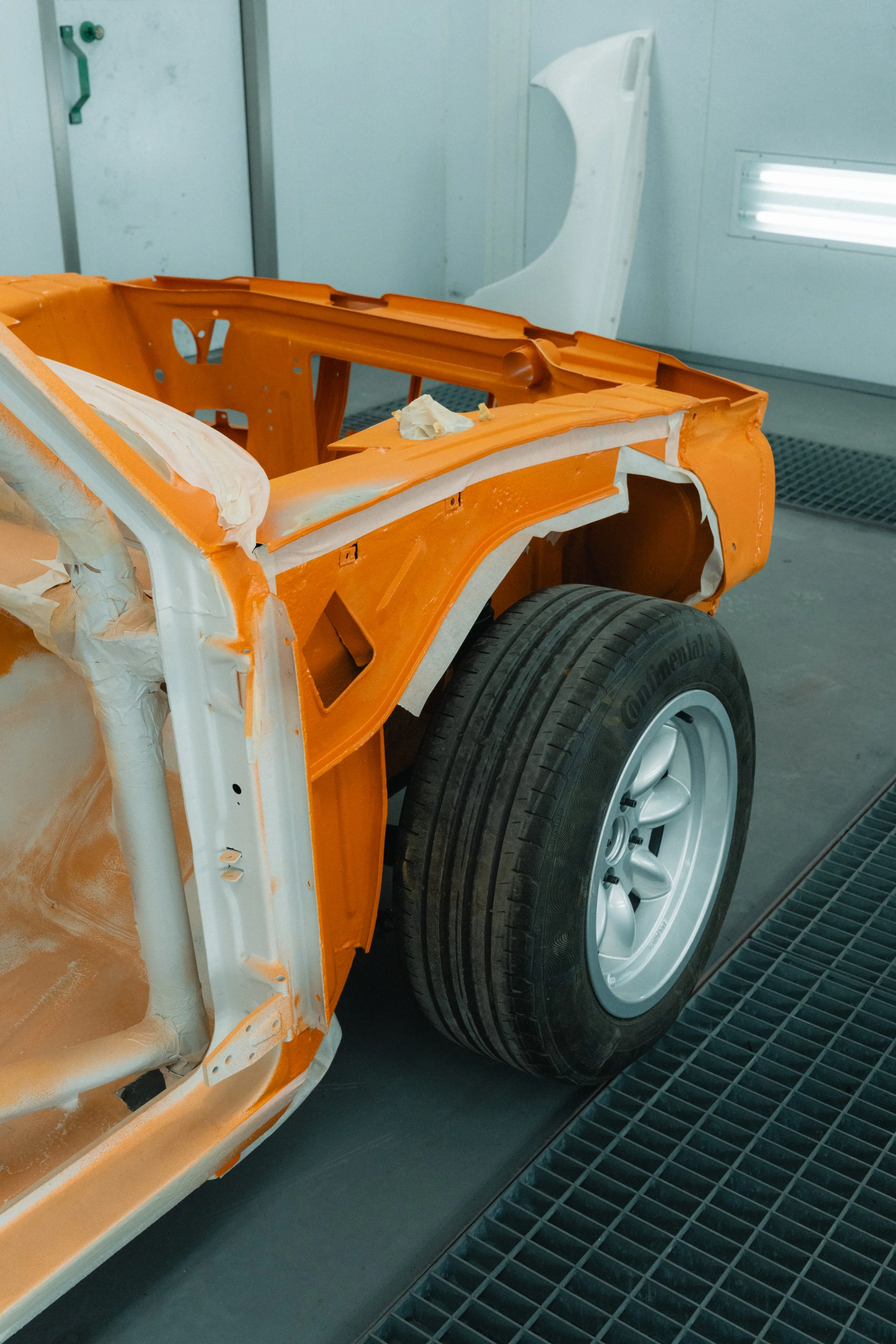 Detailfoto van oranje gespoten BMW oldtimer frame in de spuitcabine van Garage van Beek Soesterberg