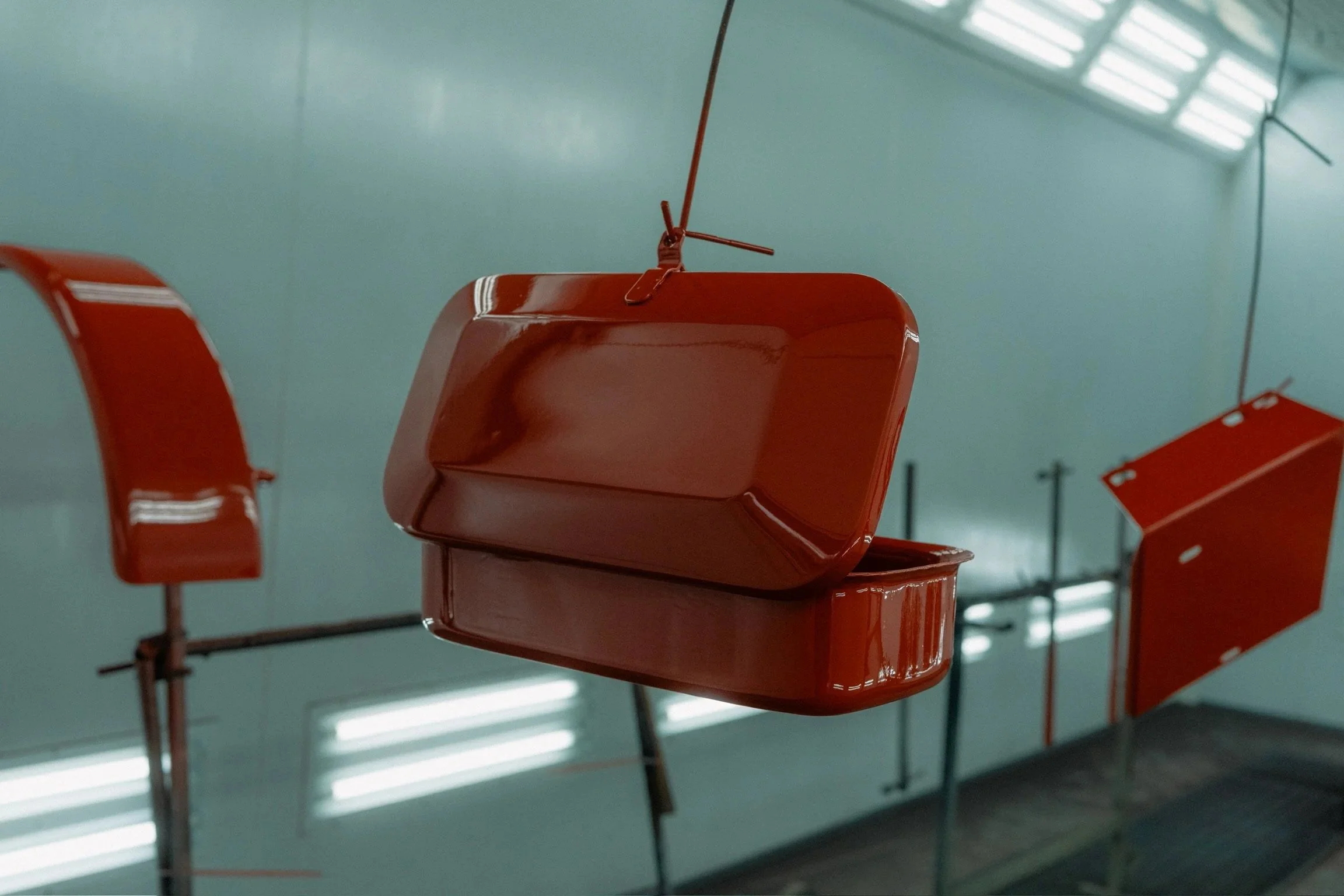 Rode tractor onderdelen van Güldner G30S hangend in spuitcabine bij Garage van Beek Soesterberg