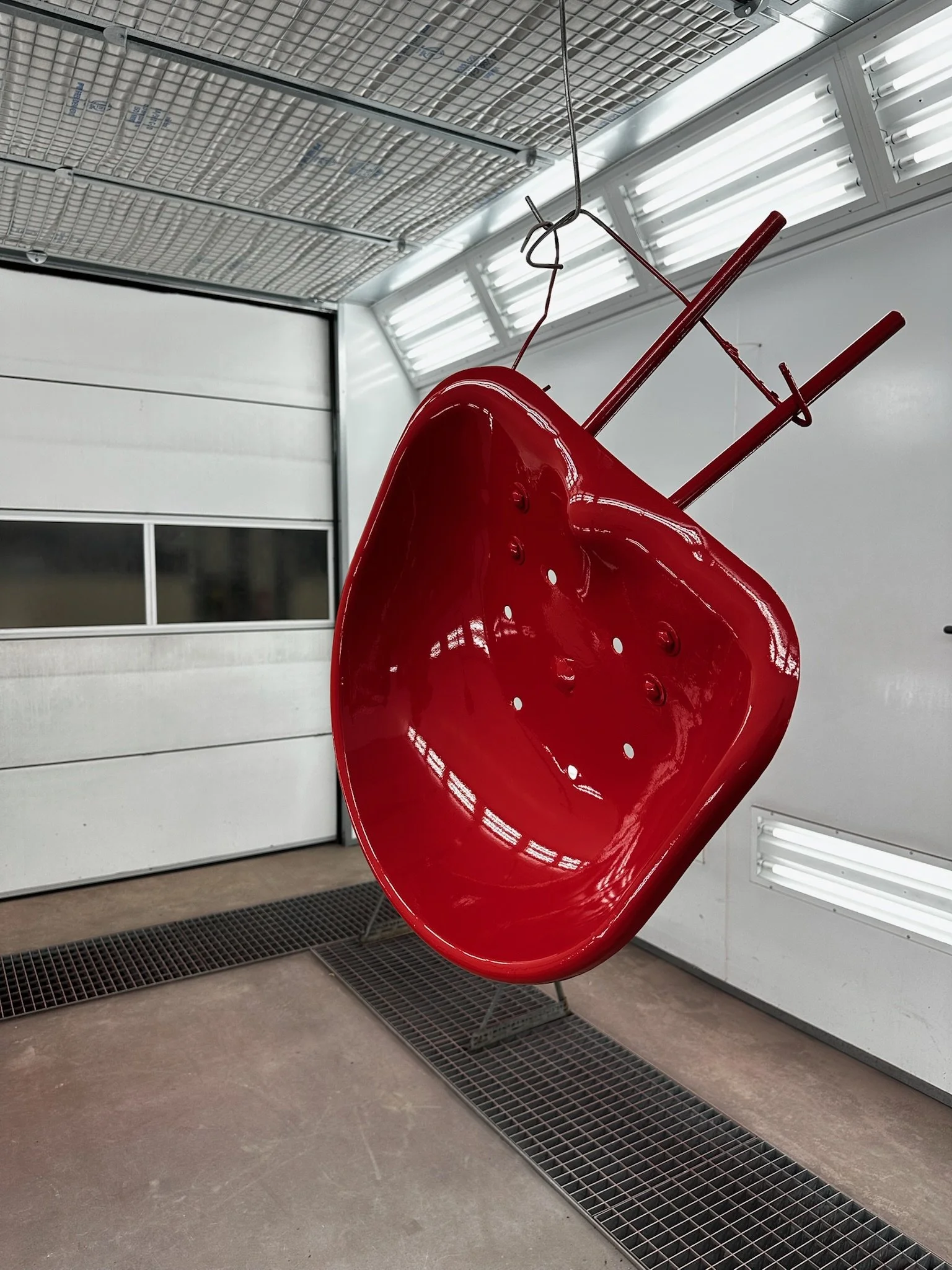 Gespoten rode tractorzitting van Güldner G30S hangend in de spuitcabine van Garage van Beek Soesterberg