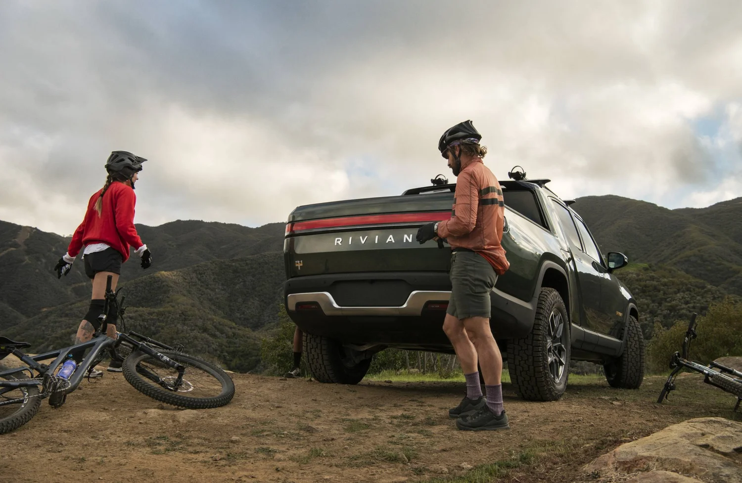 Two mountain bikers next to a Rivian R1T