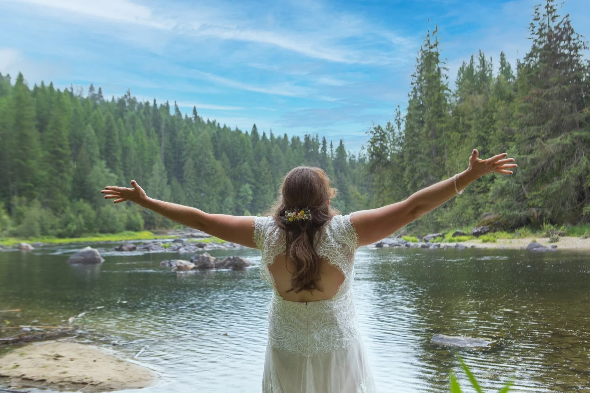Bride taking a moment to take it all in on the rivers edge of this happy hippy wedding venue in the woods but not far from town