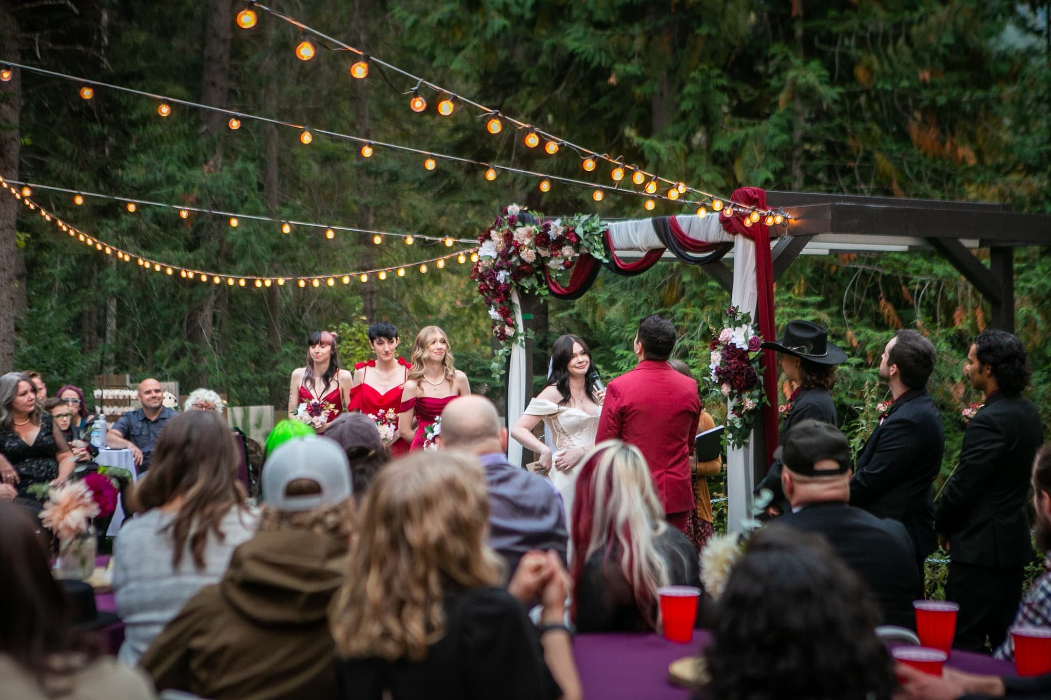 Wedding ceremony at dusk under towering cedar trees at Cedar River Wedding Venue in Priest River, Idaho, with gentle river breezes and soft, golden light creating an intimate, magical atmosphere.