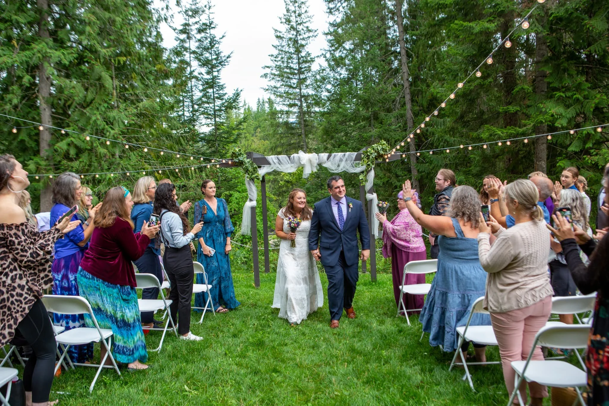 Large wedding in the natural setting along the river under gigantic shade trees offering shade and cool in the heat of summer. 