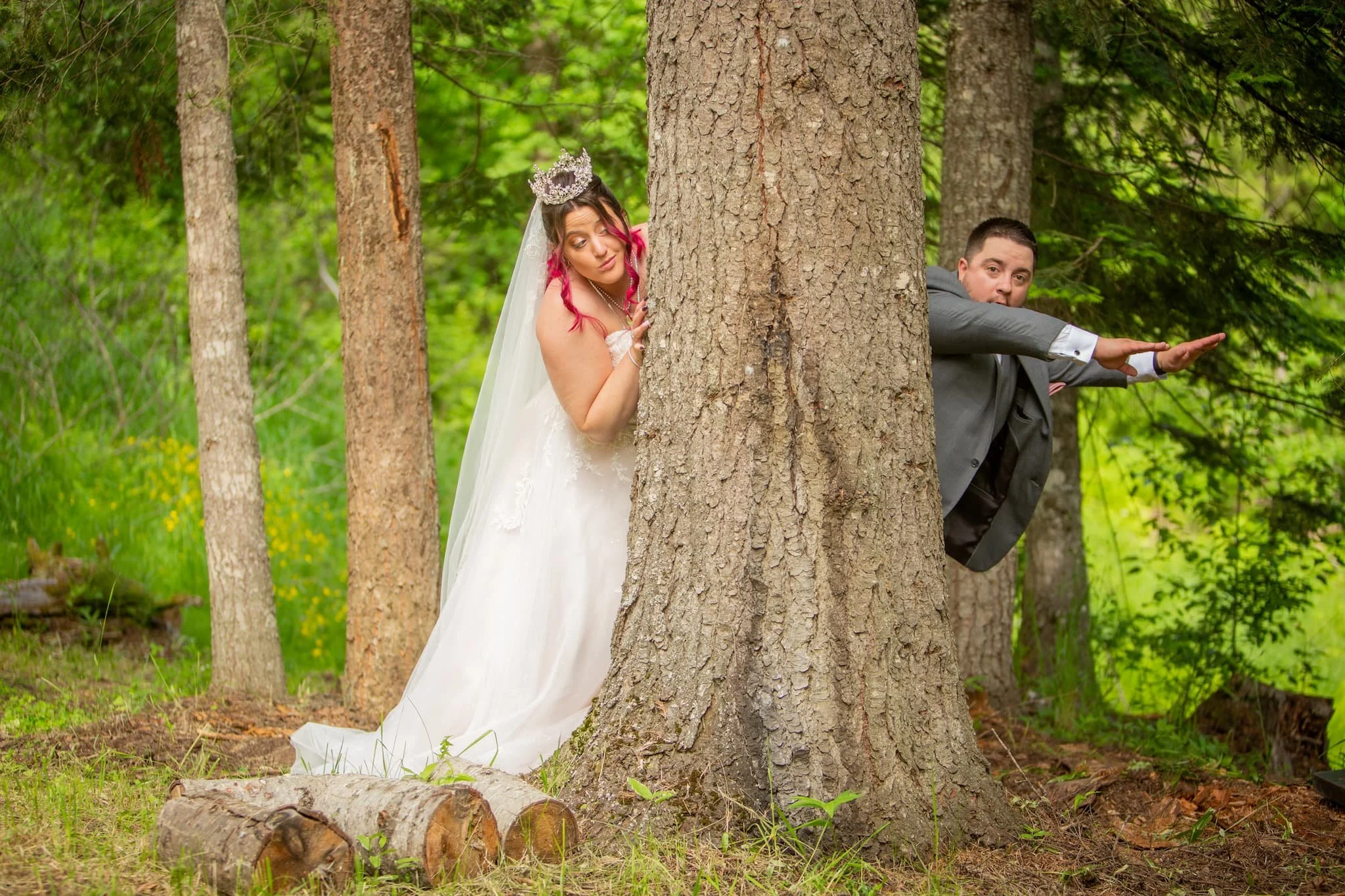 Bride and groom being playful behind a large cedar tree at Cedar River Weddings a romantic riverside wedding venue near Spokane Coeur d’Alene and Priest Lake