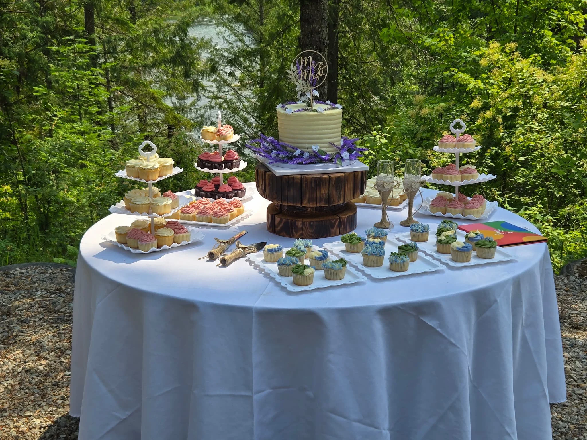 Round wedding table at Cedar River Wedding Venue in Priest River, Idaho, styled with soft linens, curated florals, and the couple’s cake, showcasing an intimate and elegantly relaxed reception setup.