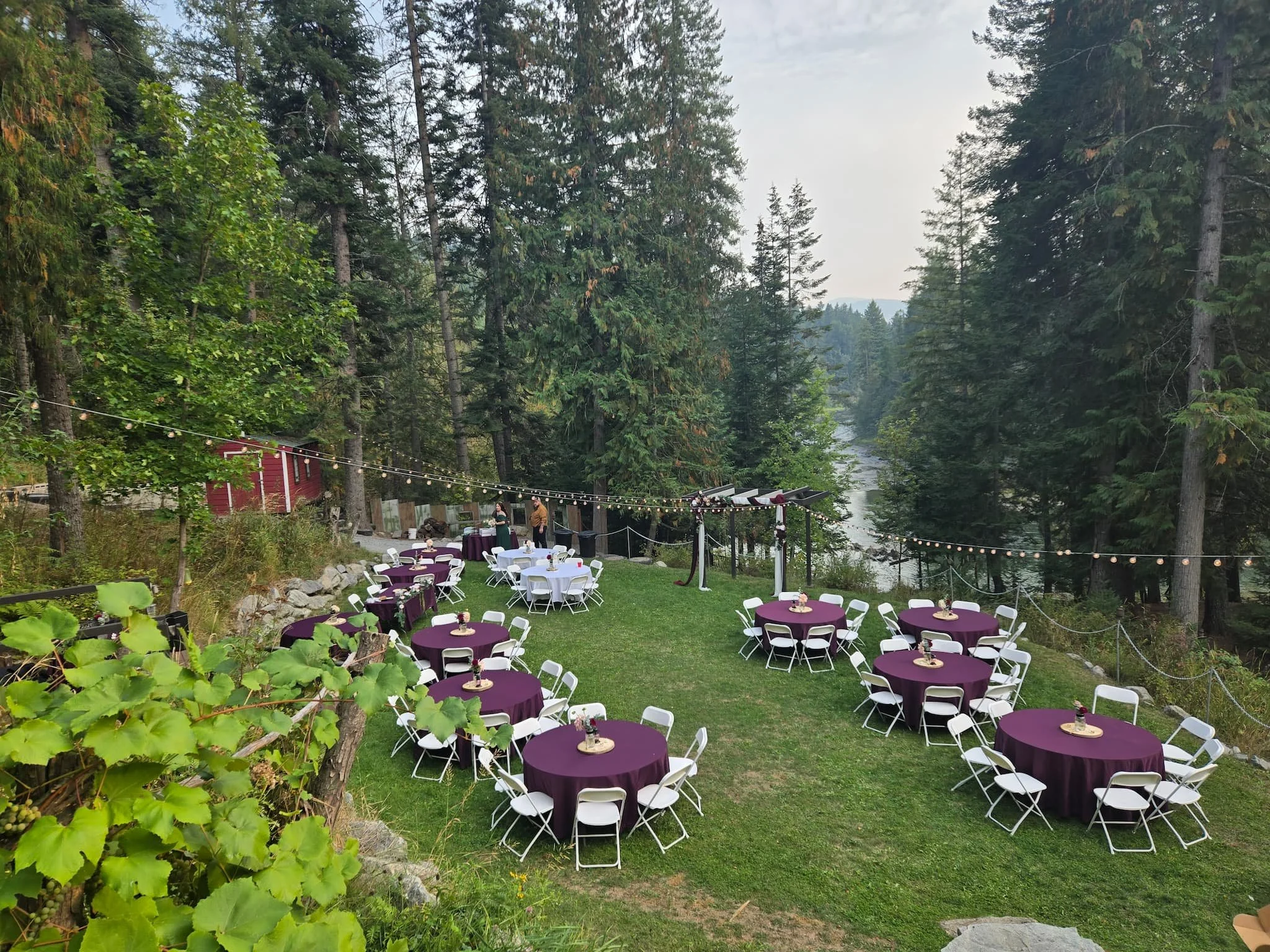 Scenic view of the ceremony area at Cedar River Wedding Venue in Priest River, Idaho, overlooking the peaceful river and surrounded by towering cedar trees, captured in soft pre-wedding light.