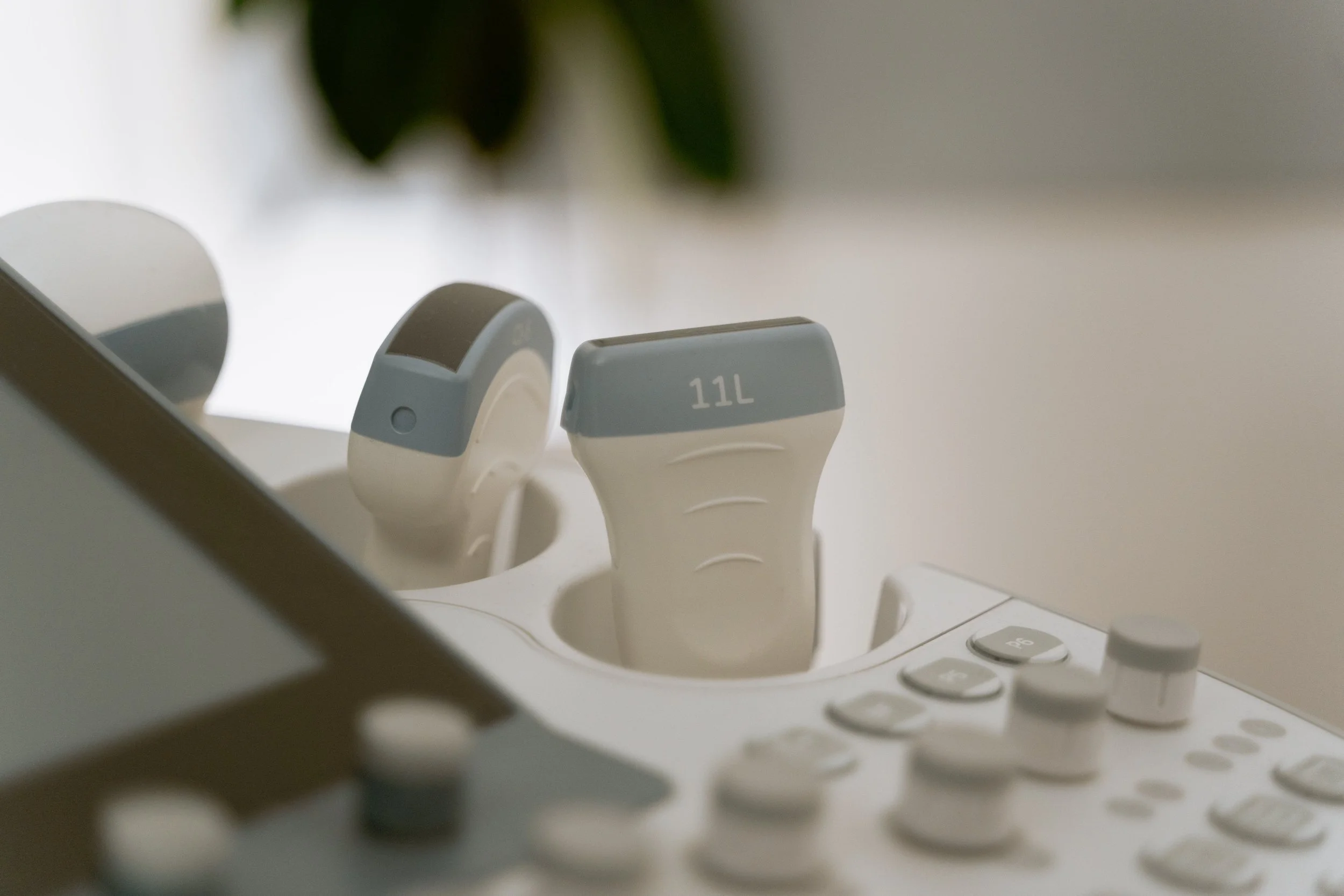 Ultrasound machine with probes labeled 11L and 11 on a white surface in a medical setting.