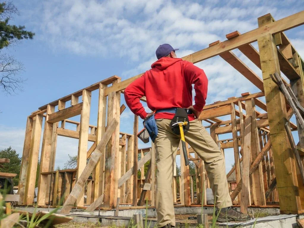 Tradesperson standing at a jobsite looking at a timber frame