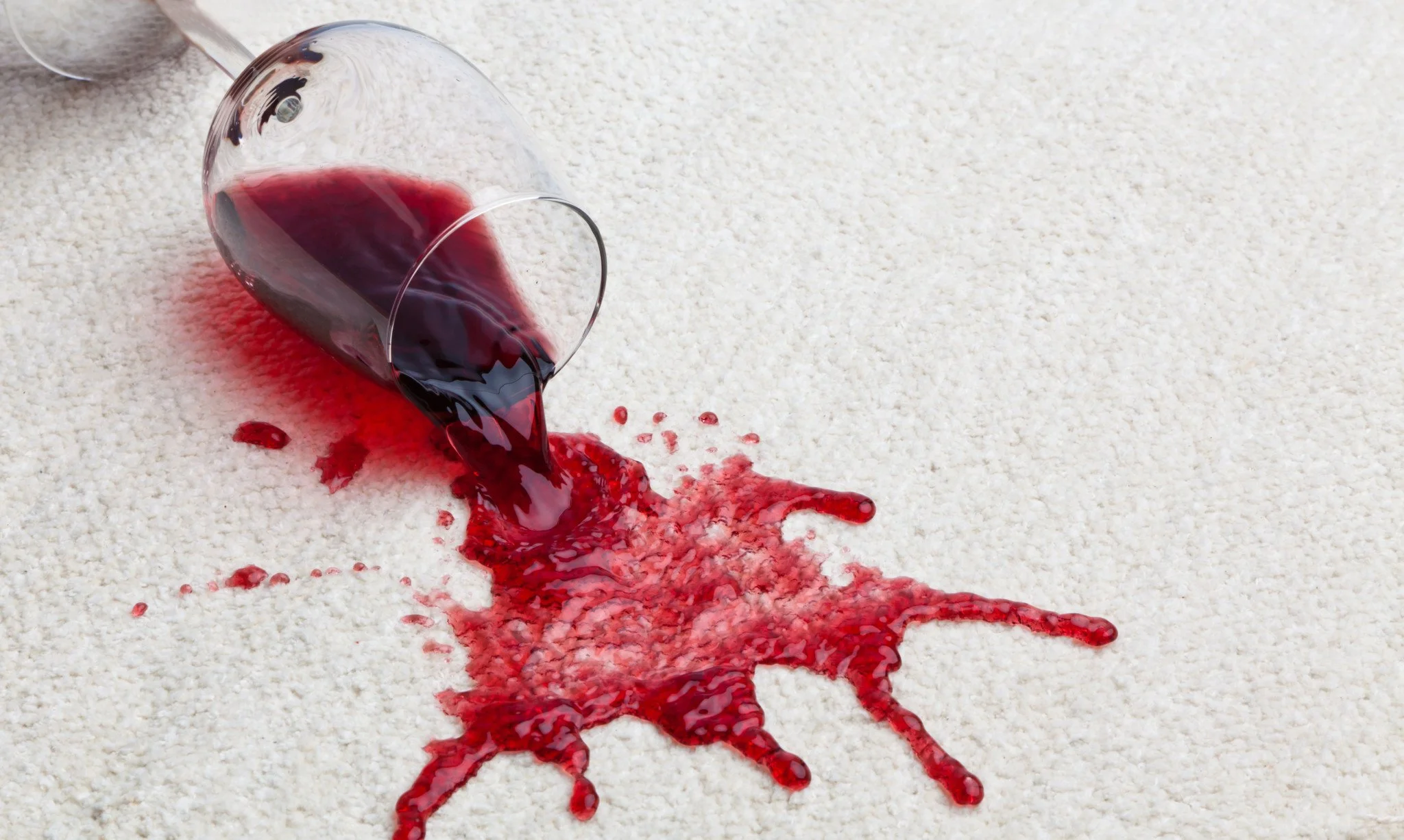 glass of red wine spilling onto carpet