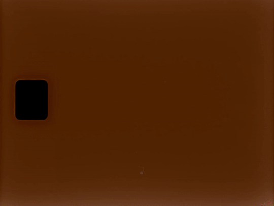 Close-up of a brown surface with a small black rounded rectangle in the top left corner.