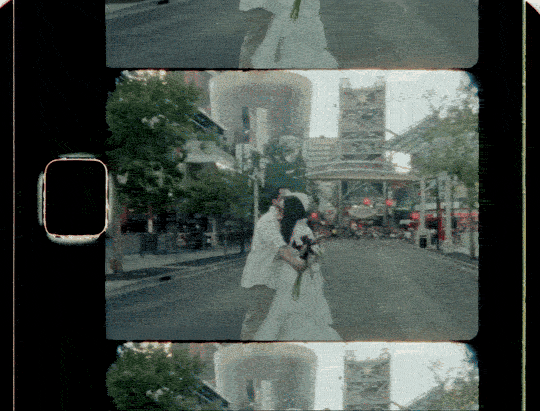 A person and a woman are walking on a city street, reflected in a film strip with multiple frames. The scene includes buildings, trees, and vehicles.