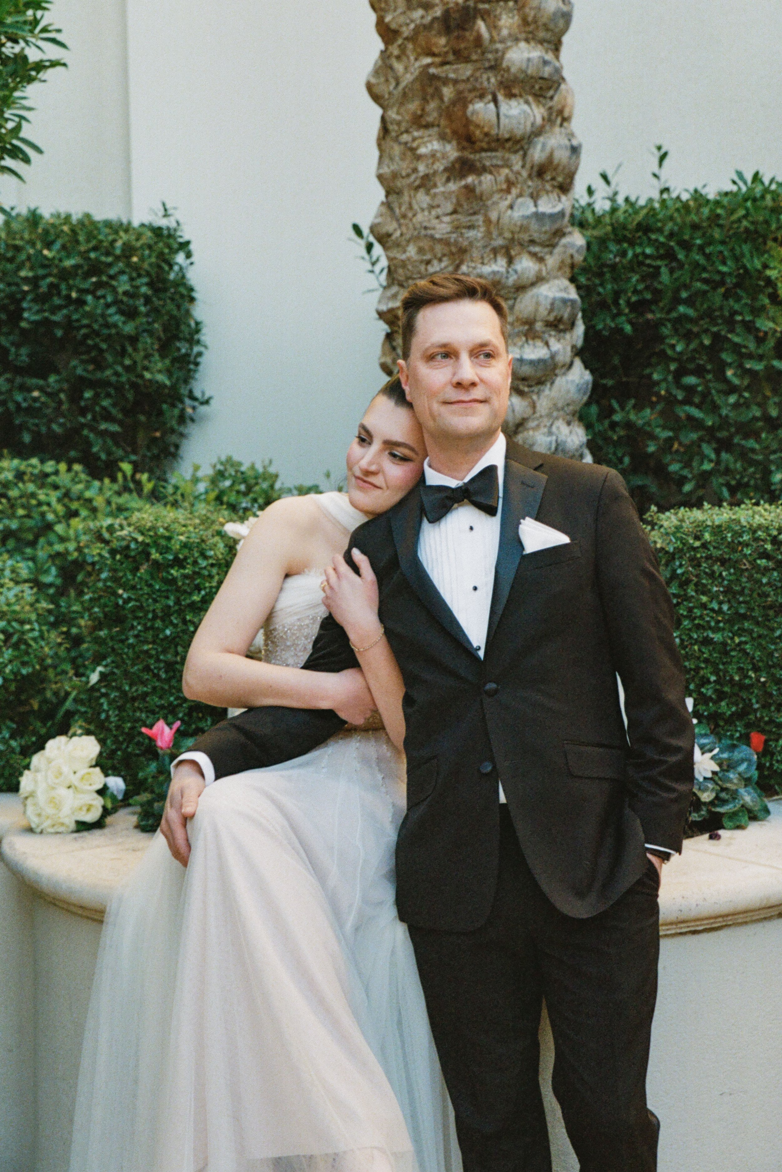 brides and groom posing in a garden 