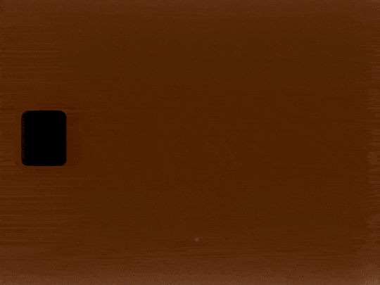 A wooden surface with a black rectangular object on the left side.